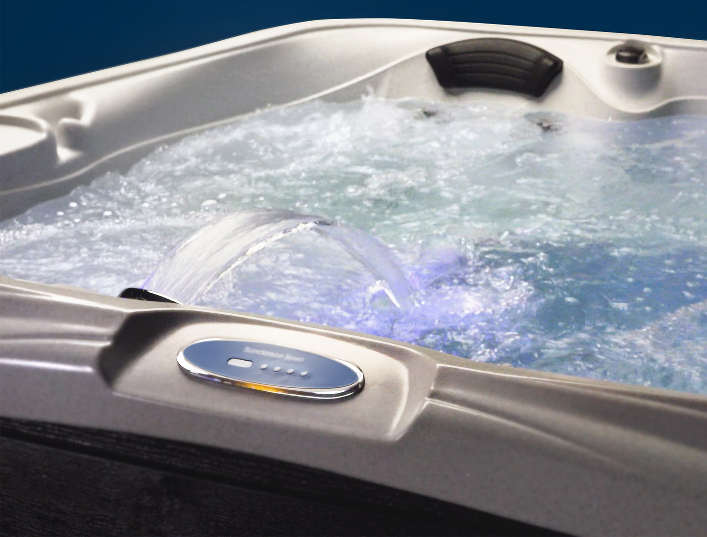 A hot tub filled with bubbling water, featuring jets and a control panel on the side.