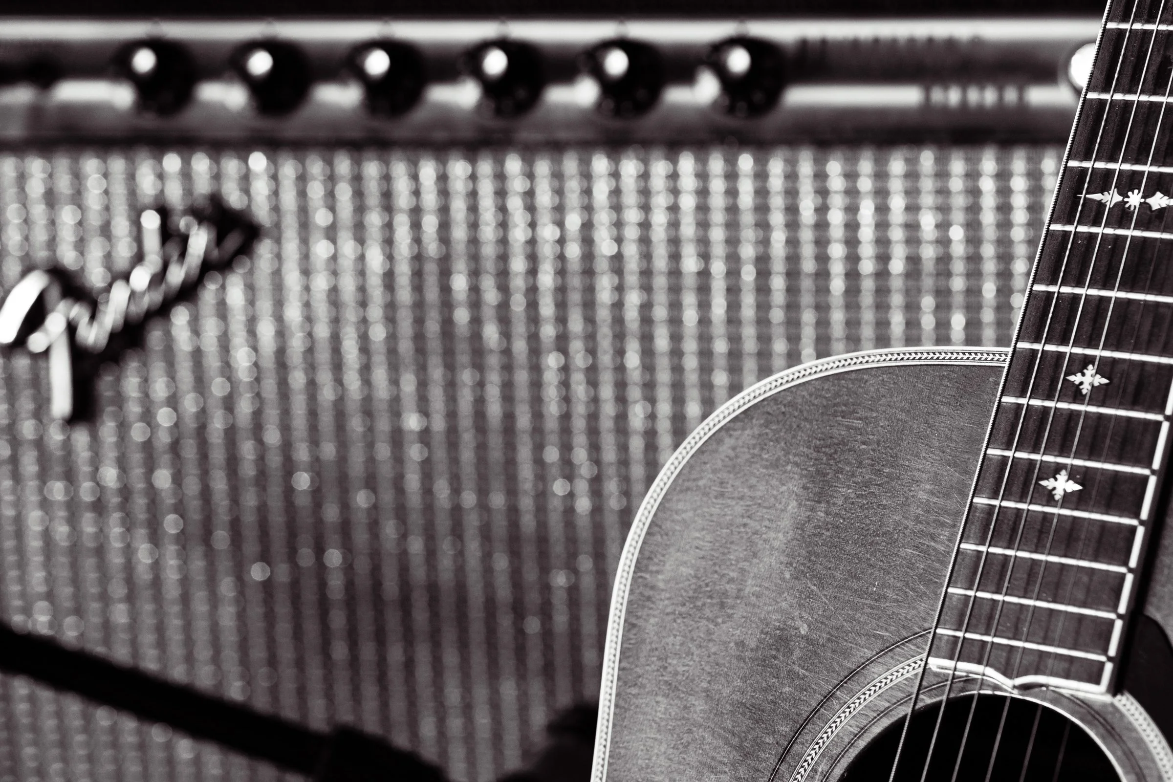 Close-up of an acoustic guitar leaning against a textured amplifier.