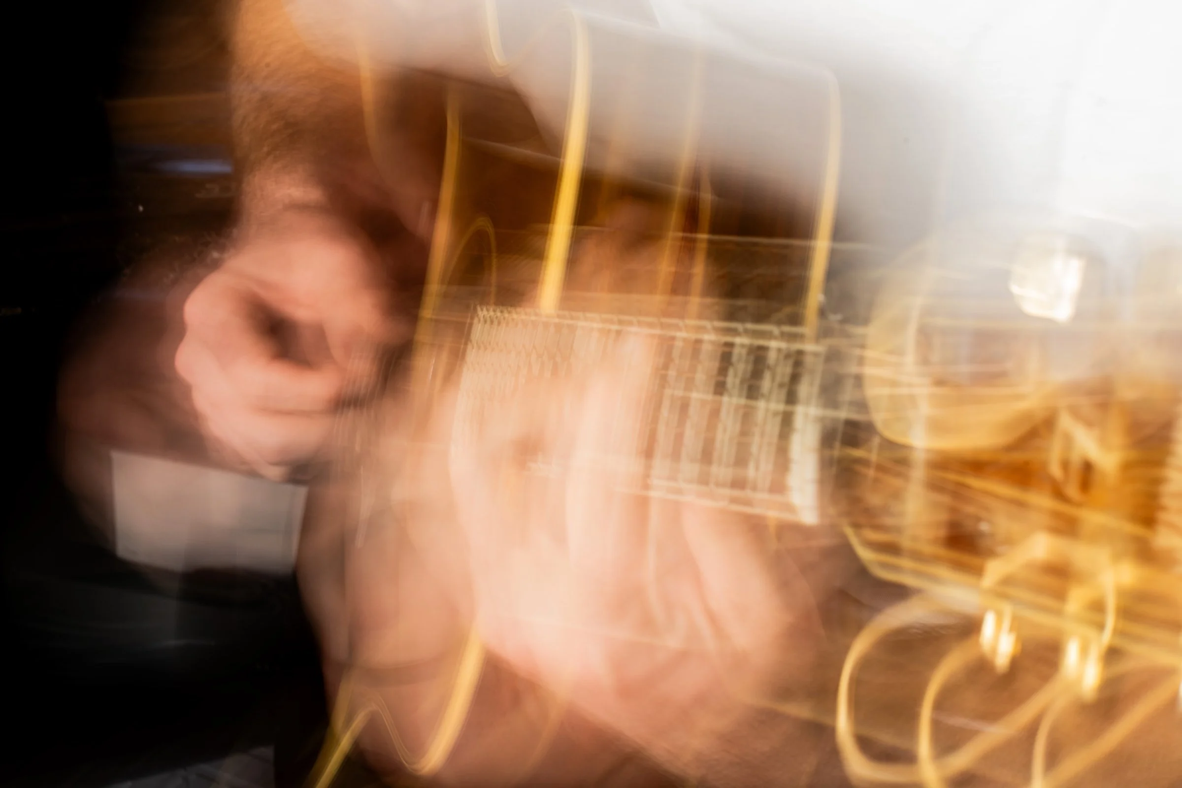 A blurry image of a person sitting at a table, with various objects and chairs in the background, captured in motion or with a slow shutter speed.