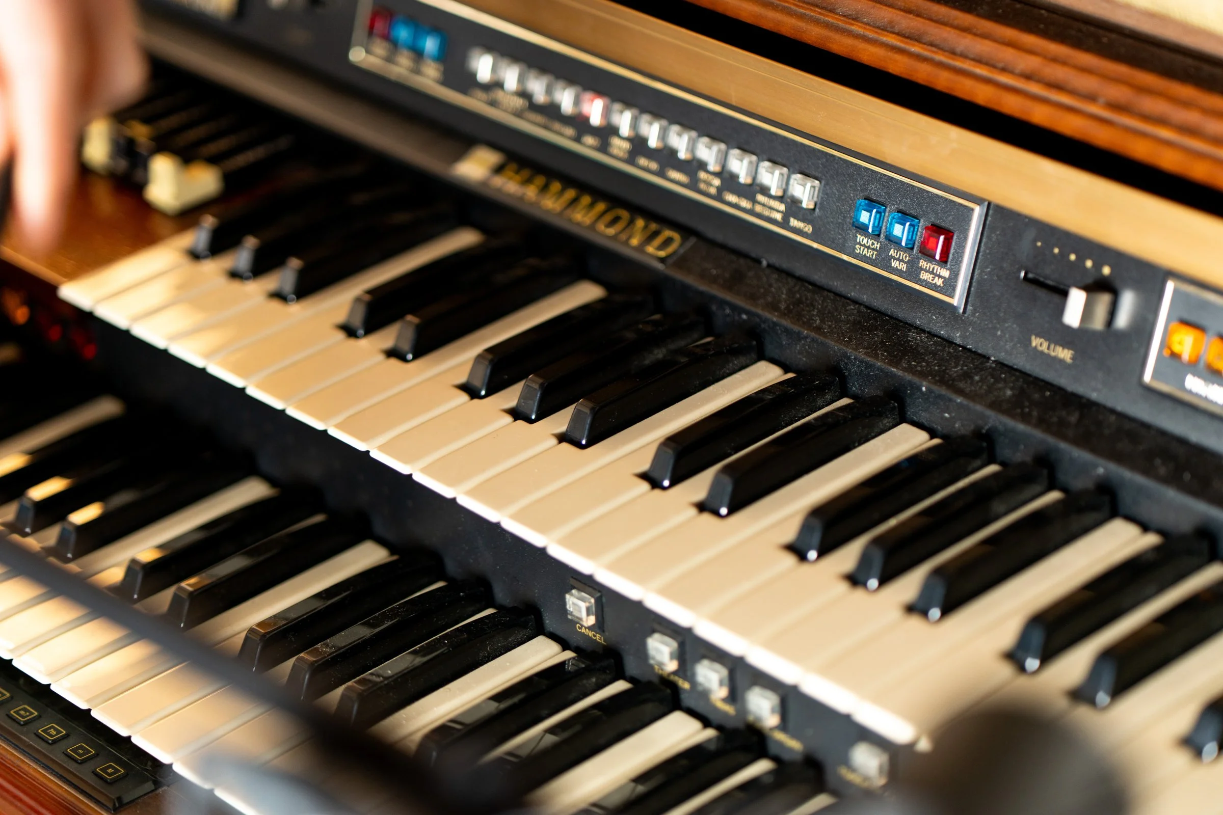 Close-up of a vintage electronic organ with black and white keys, control buttons, and labels on the panel