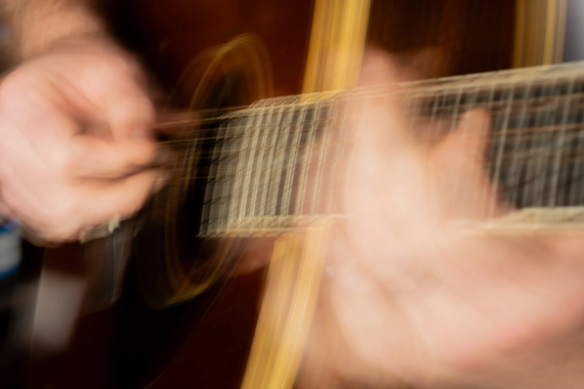 A person playing an acoustic guitar, captured with motion blur.
