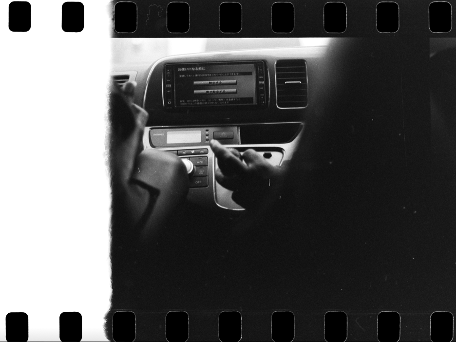 A person adjusting the car's climate control system and radio on the dashboard.
