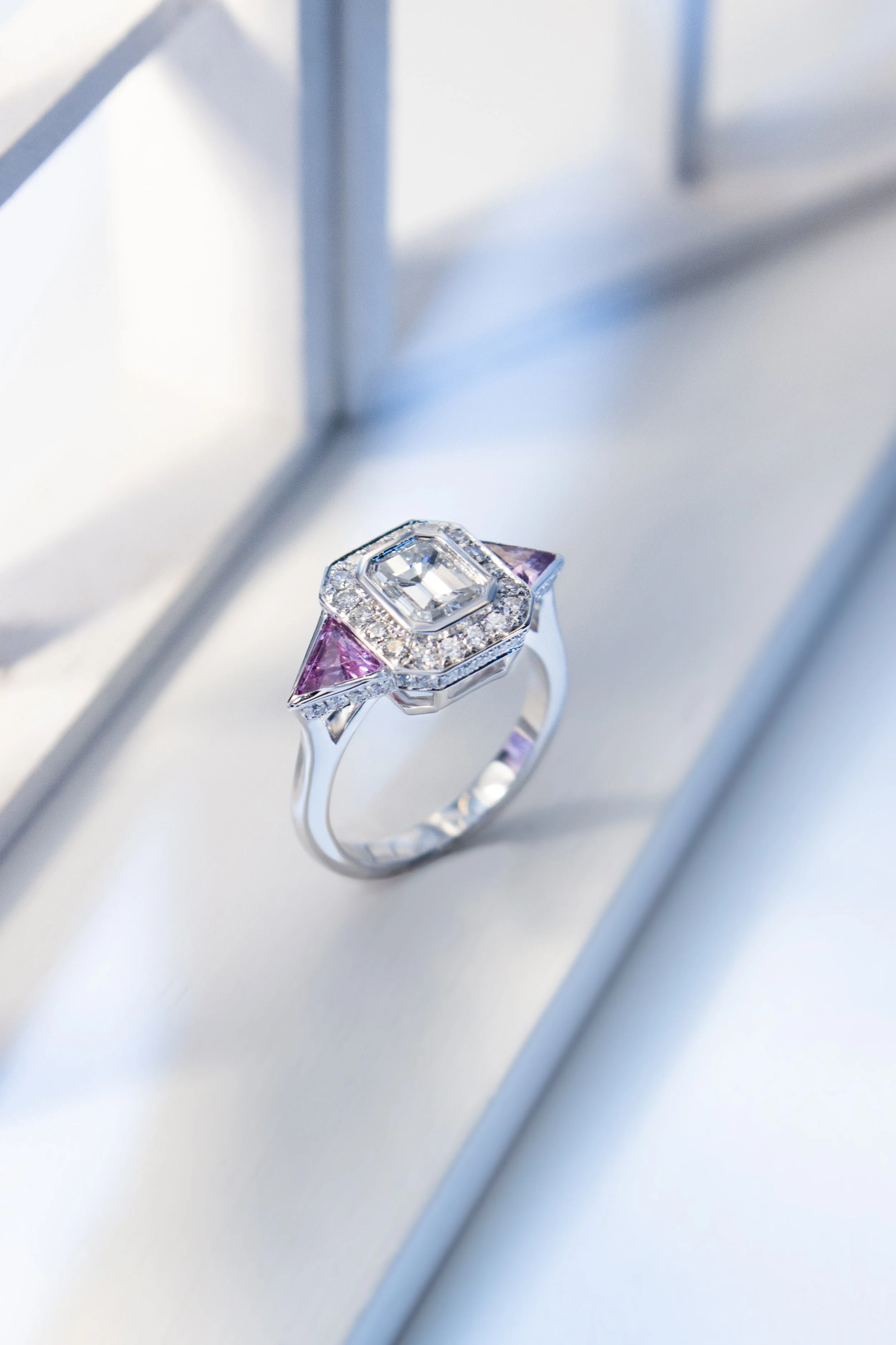 Platinum ring by Sophie Cudworth, set with clients own diamonds and two specially cut pink sapphires in a halo design, bespoke jewellery design 