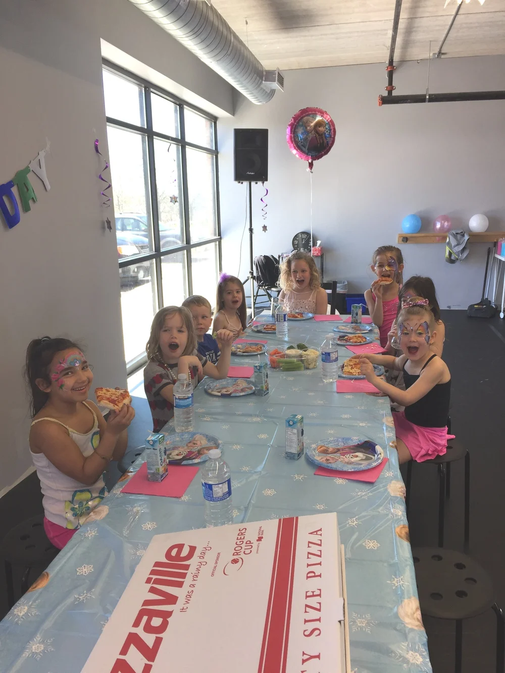 Children eating pizza together at a decorated birthday table