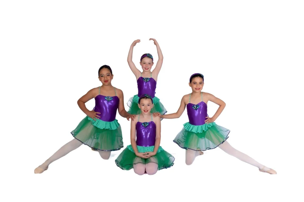 Youth ballet dancers in purple and green costumes