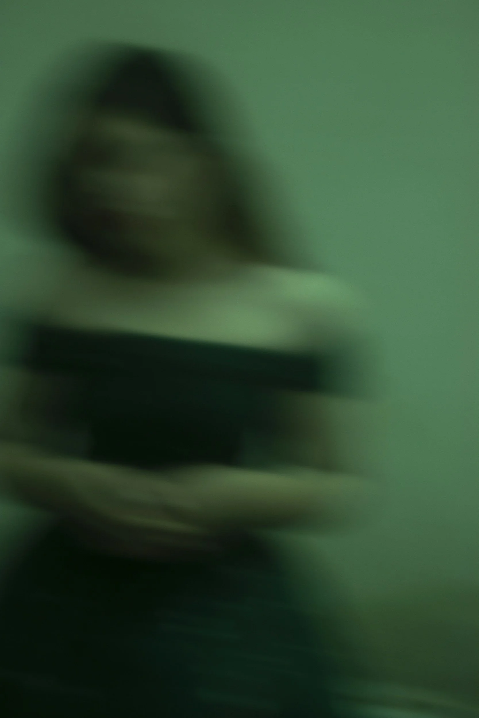 blurred out woman in black tube top green background. Sexual assault victim.