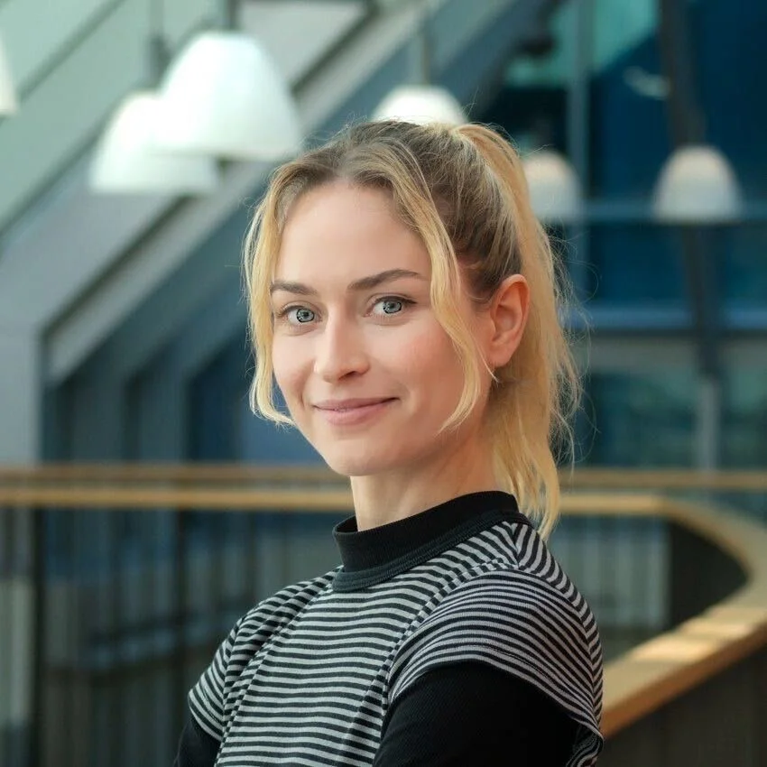 Anja smiling wearing a black and white striped shirt shirt