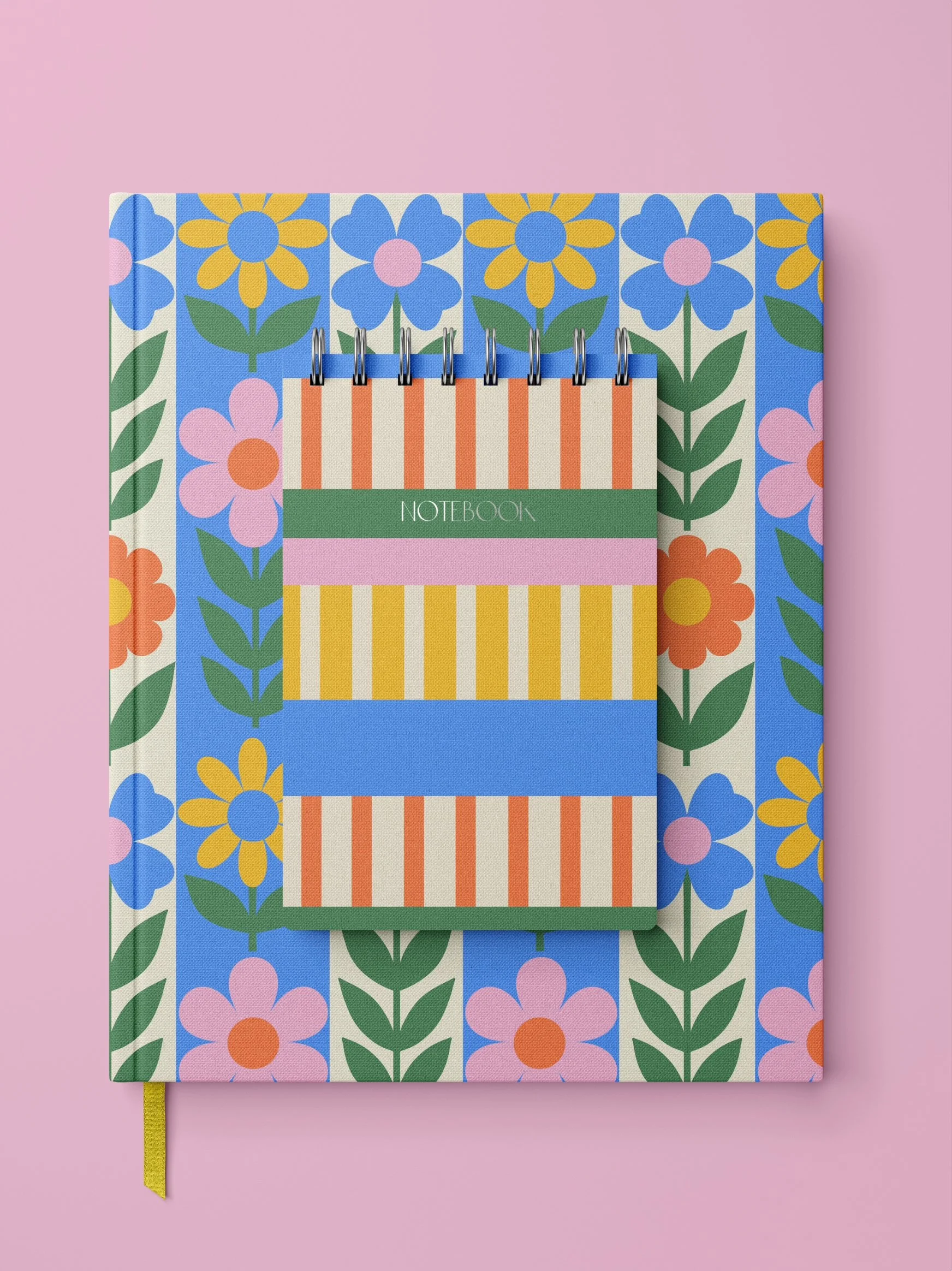 A floral-patterned notebook with a smaller striped and colourful notepad placed on top, against a pink background.