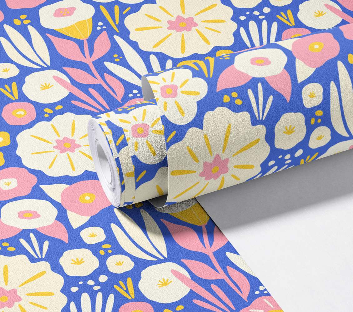 A roll of decorative floral wallpaper unrolling to show a colorful pattern of pink, yellow, and white flowers on a blue background.