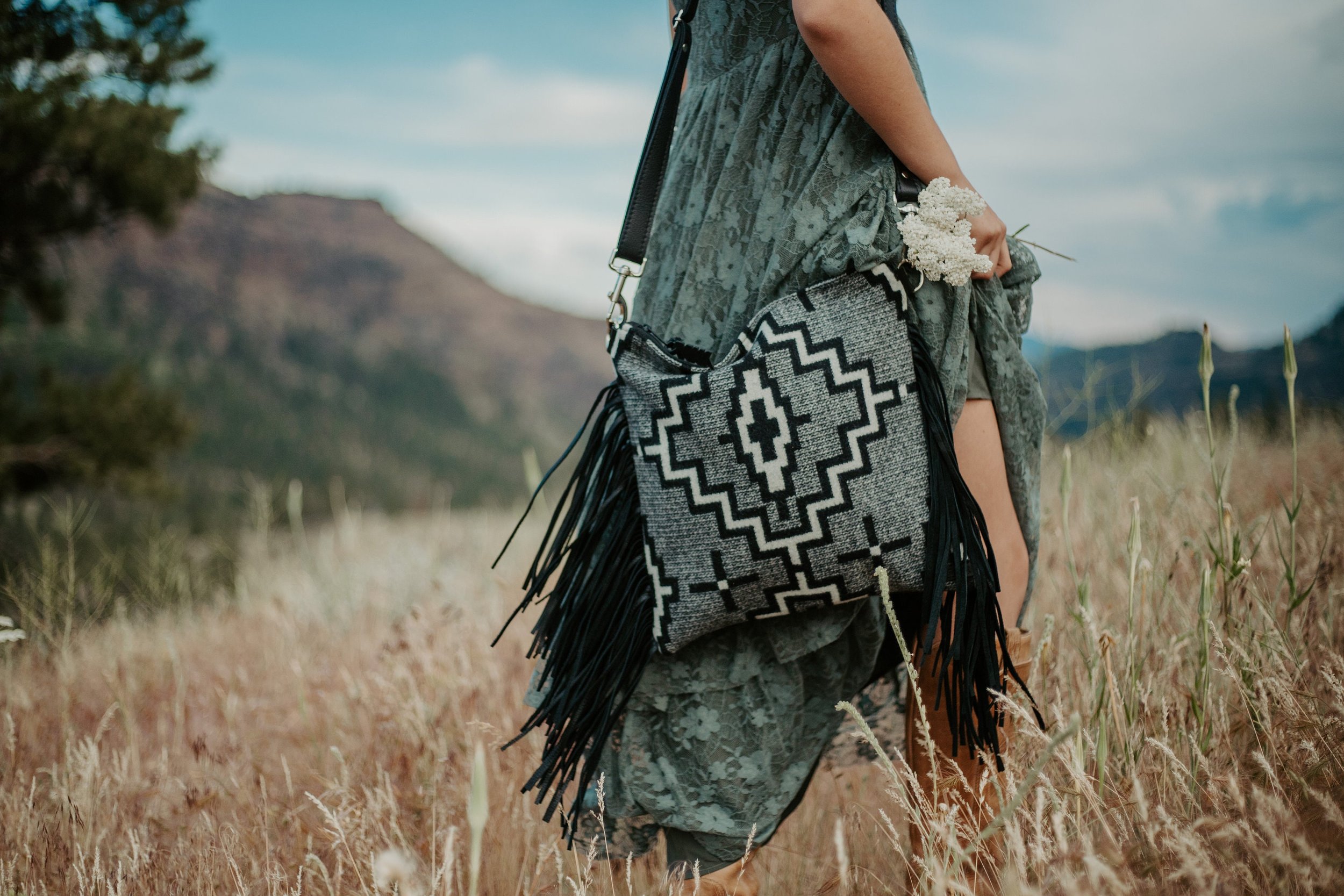 woman standingin meadow wearing a long dress and holding a purse made with Pendleton Wool Fabric in Kiva Steps and black leather
