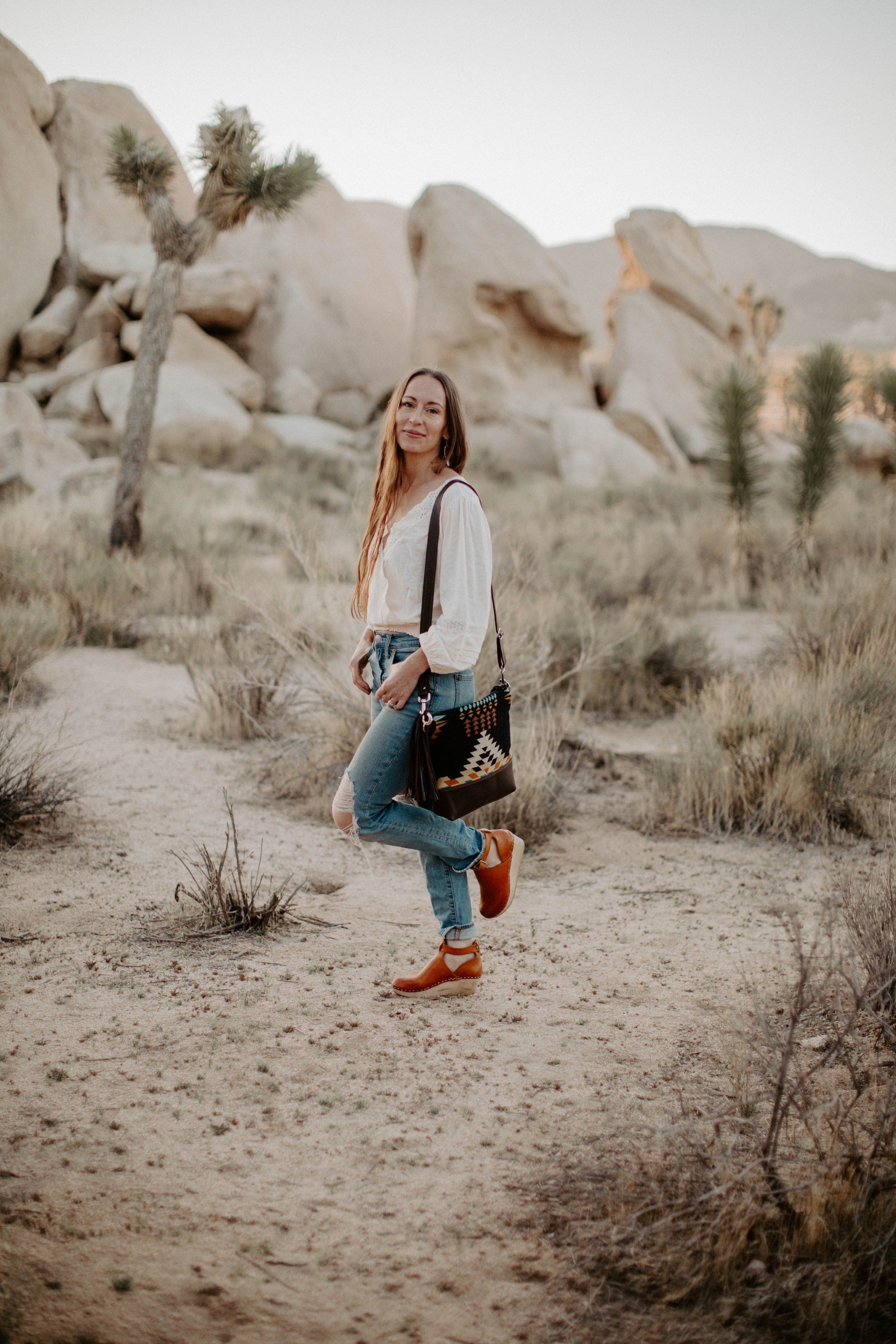 woman standing in Joshua tree wearing a small, brown shoulder bag made of Pendleton wool and Oregon leather