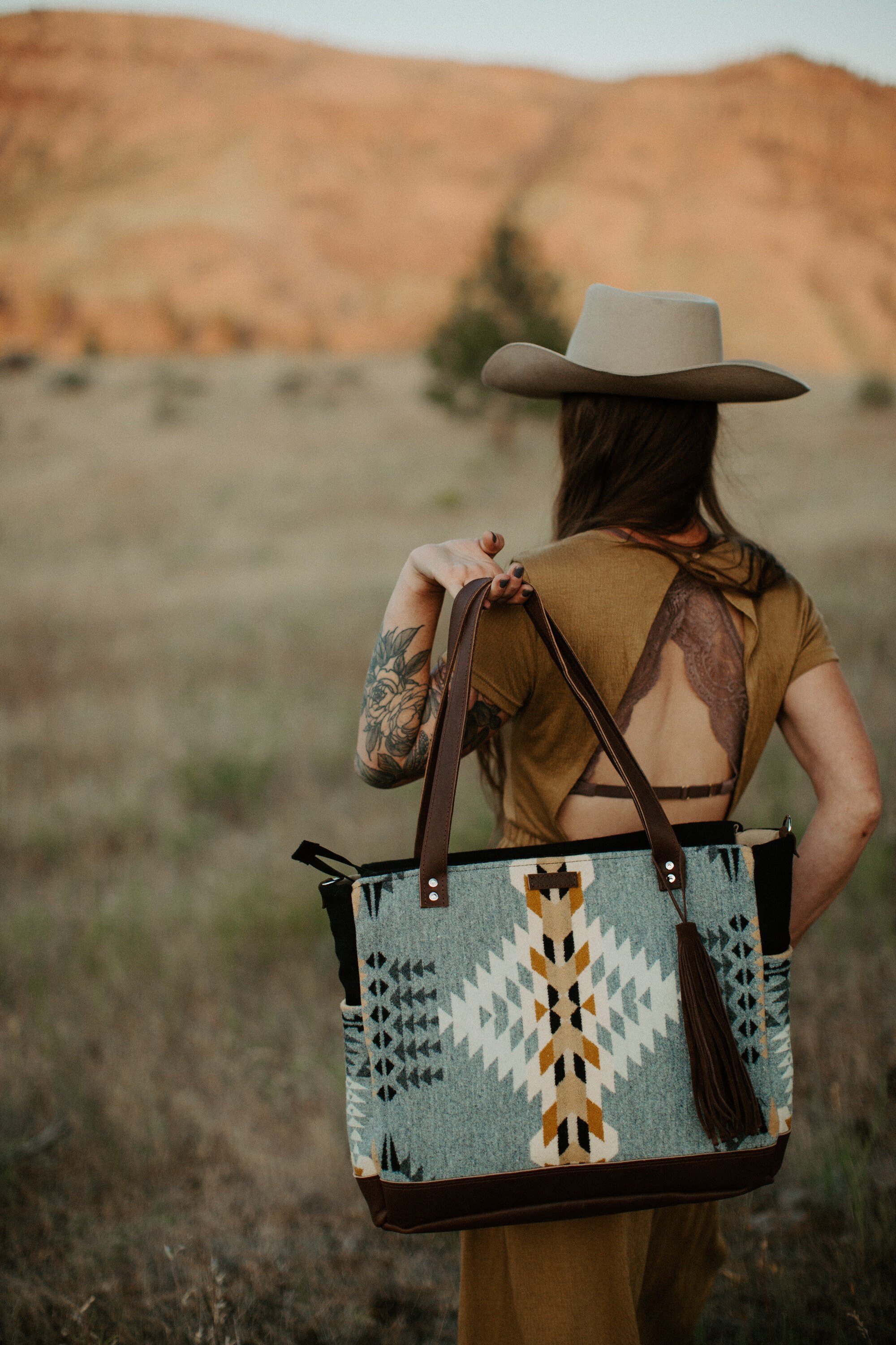 woman holding a large gray tote with leather detailing over her back