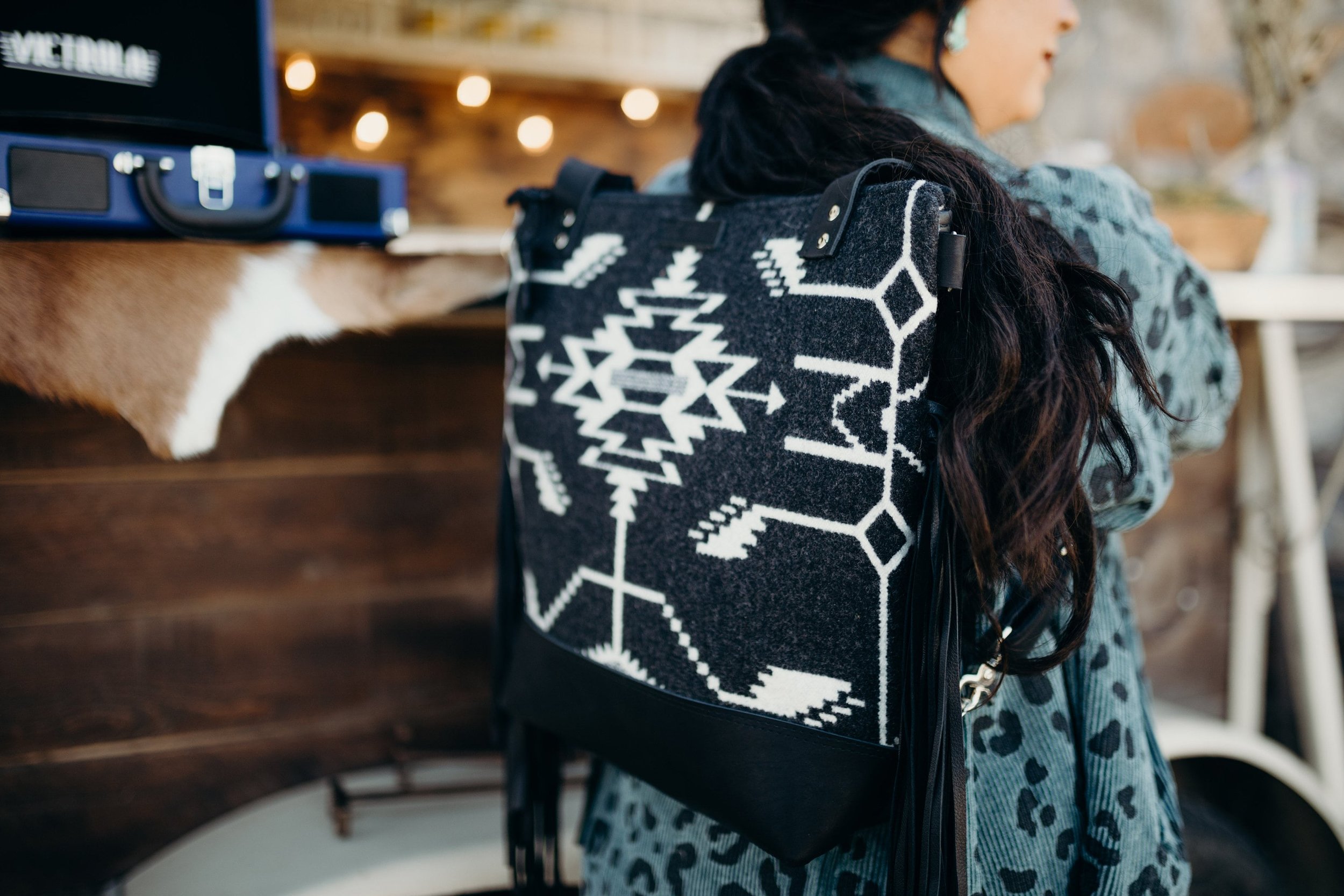 woman wearing a black and white native back pack purse in a coffee shop