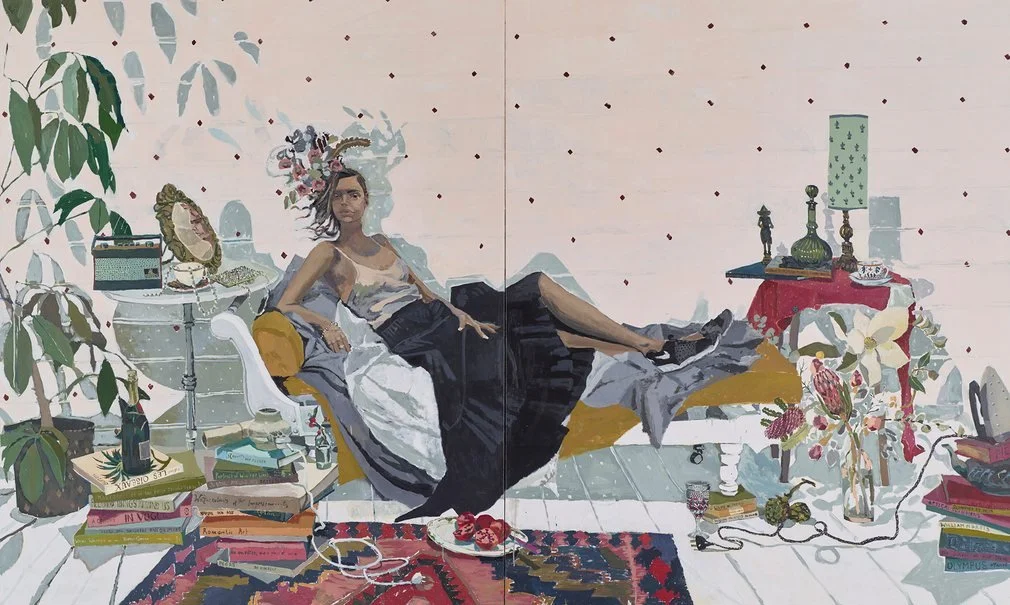 A woman with an elaborate floral headpiece relaxing on a white couch in a cluttered room with books, plants, and decorative objects.