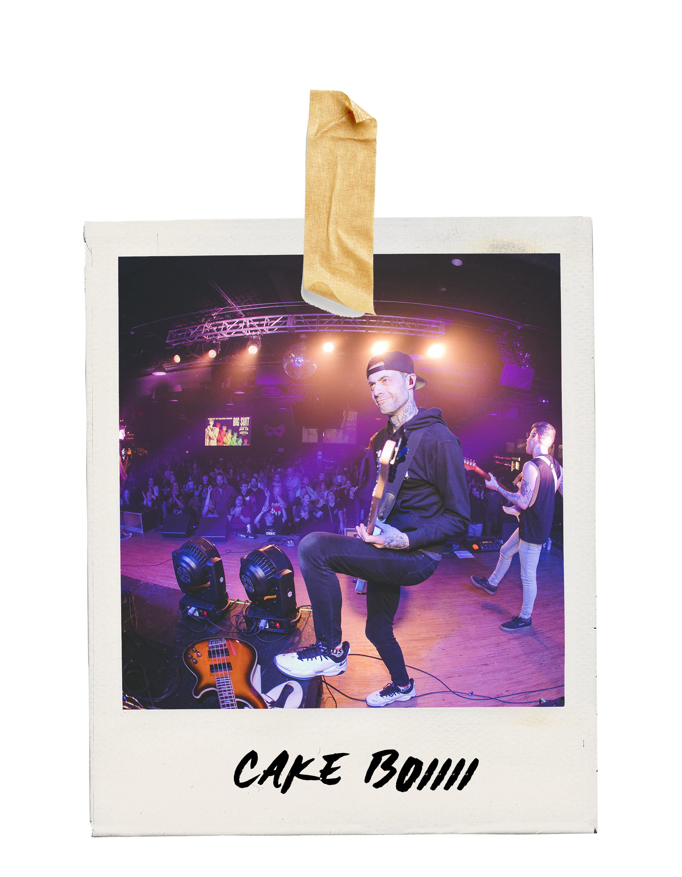 Polaroid-style photo of a live music performance at a concert, showing a man playing guitar and a crowd watching, with the text 'CAKE BOIII' written at the bottom.