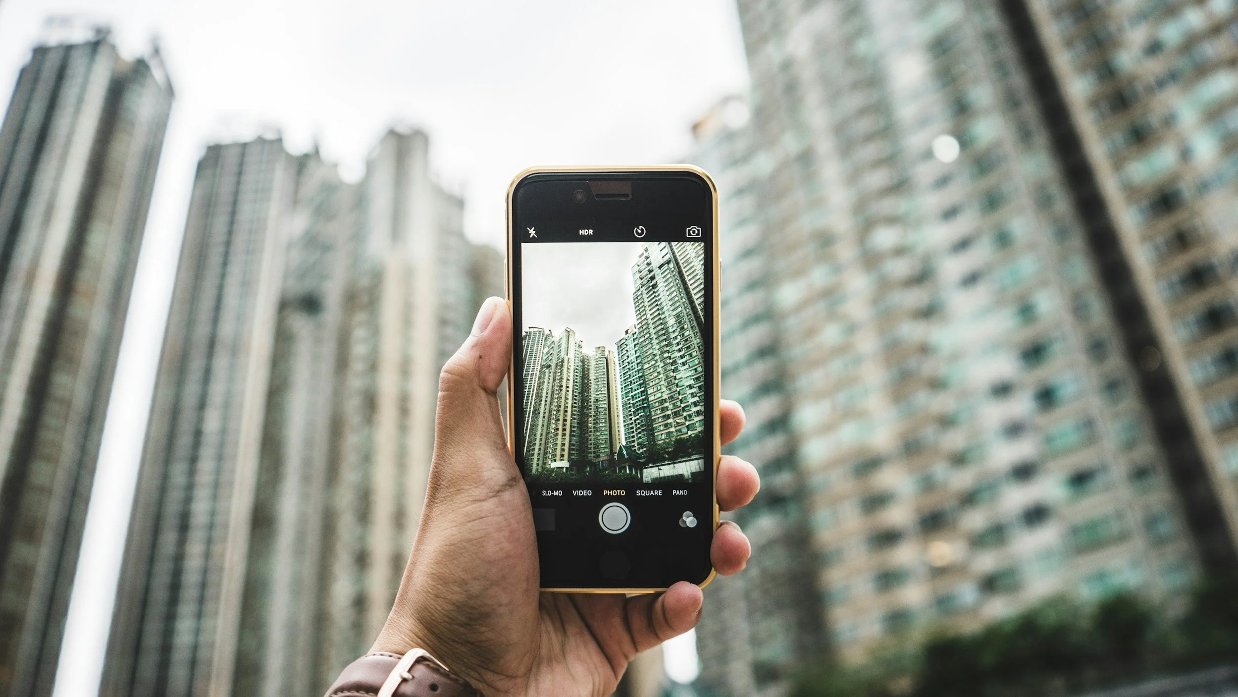 Person taking picture of city buildings on phone.