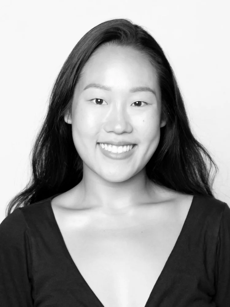 Black and white portrait of a smiling woman with long dark hair wearing a V-neck top.