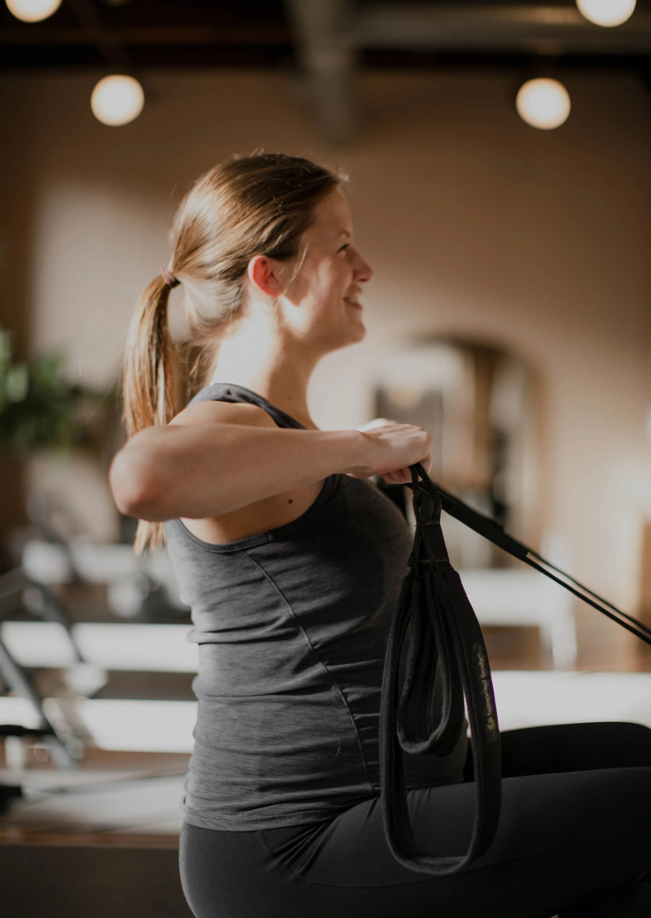 A woman in workout clothes practicing yoga or stretching in a gym or fitness studio.