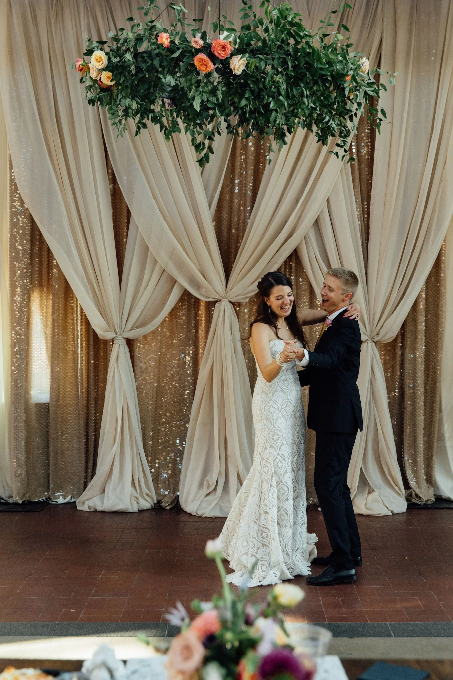 bride and groom dancing in front of a fabric draping installation