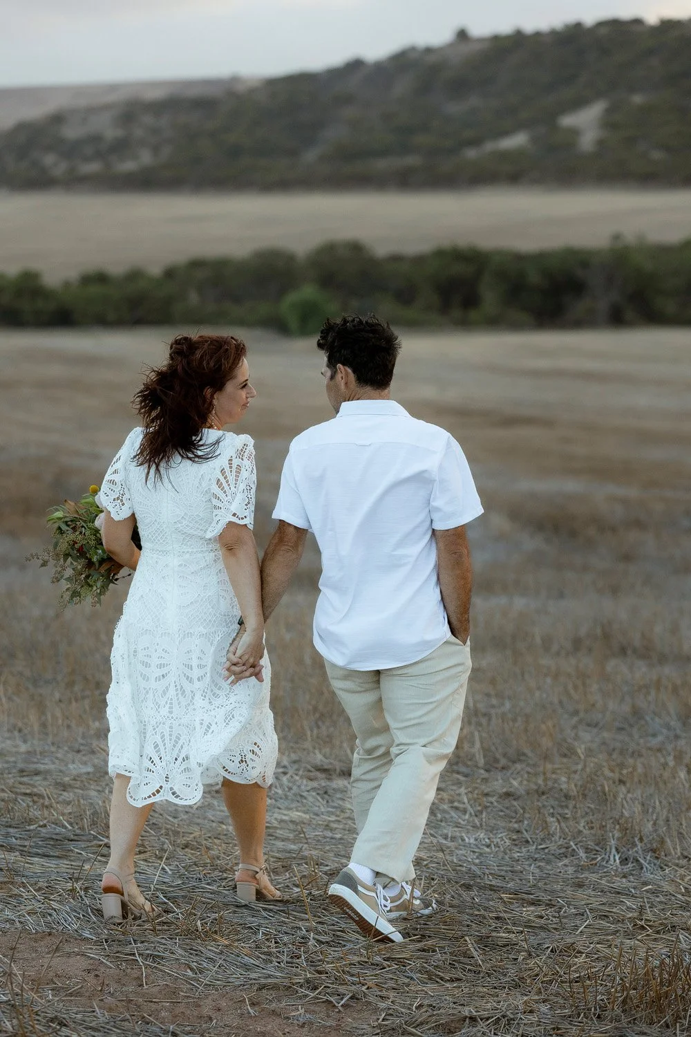 Bride & Groom walking hand in hand away form the camera in paddock