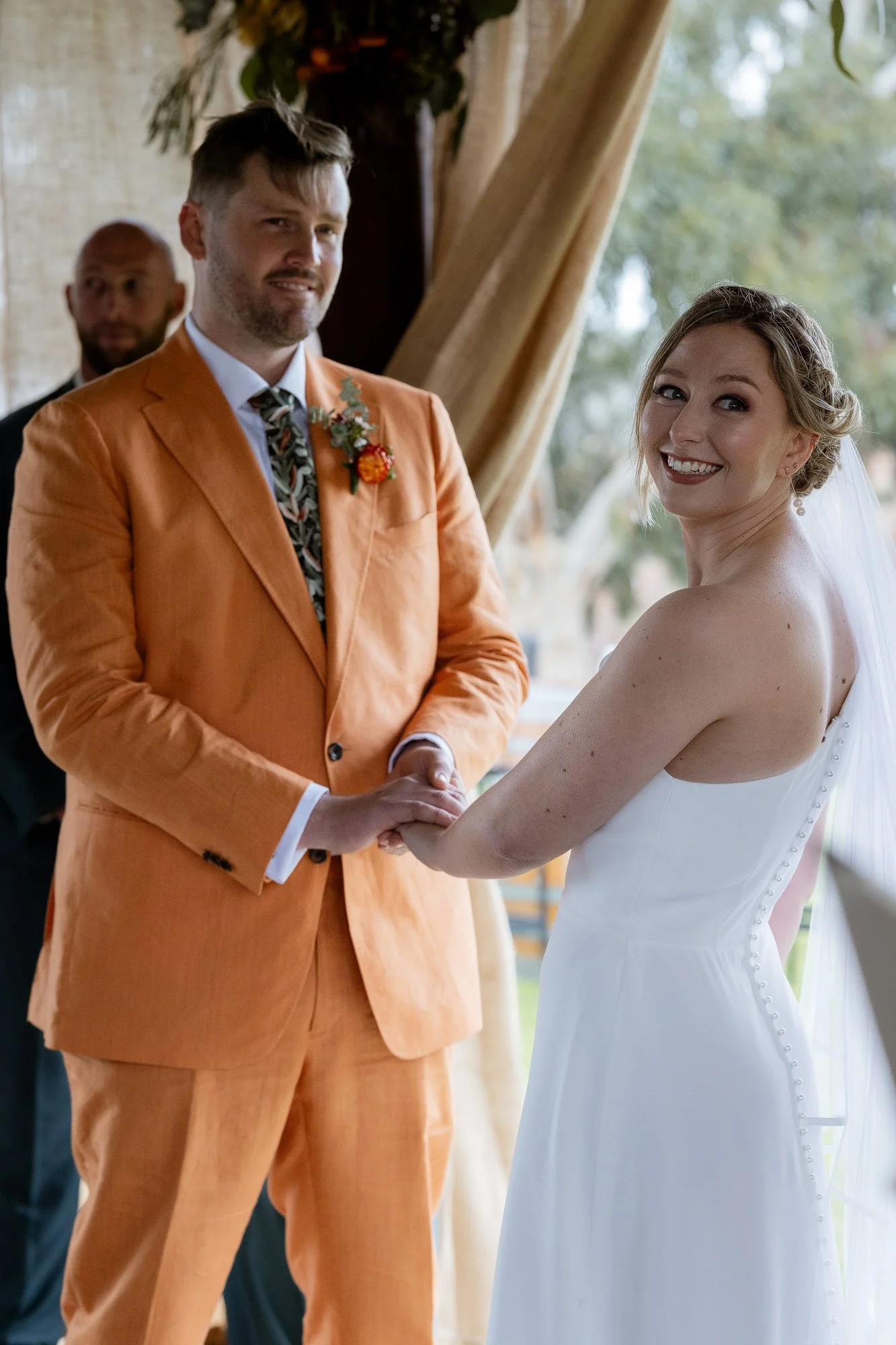 Bride and groom holding hands bride looking over shoulder at camera