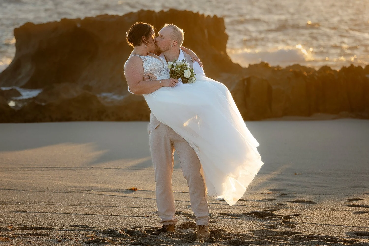 Groom holding Bride on Beach at sunset