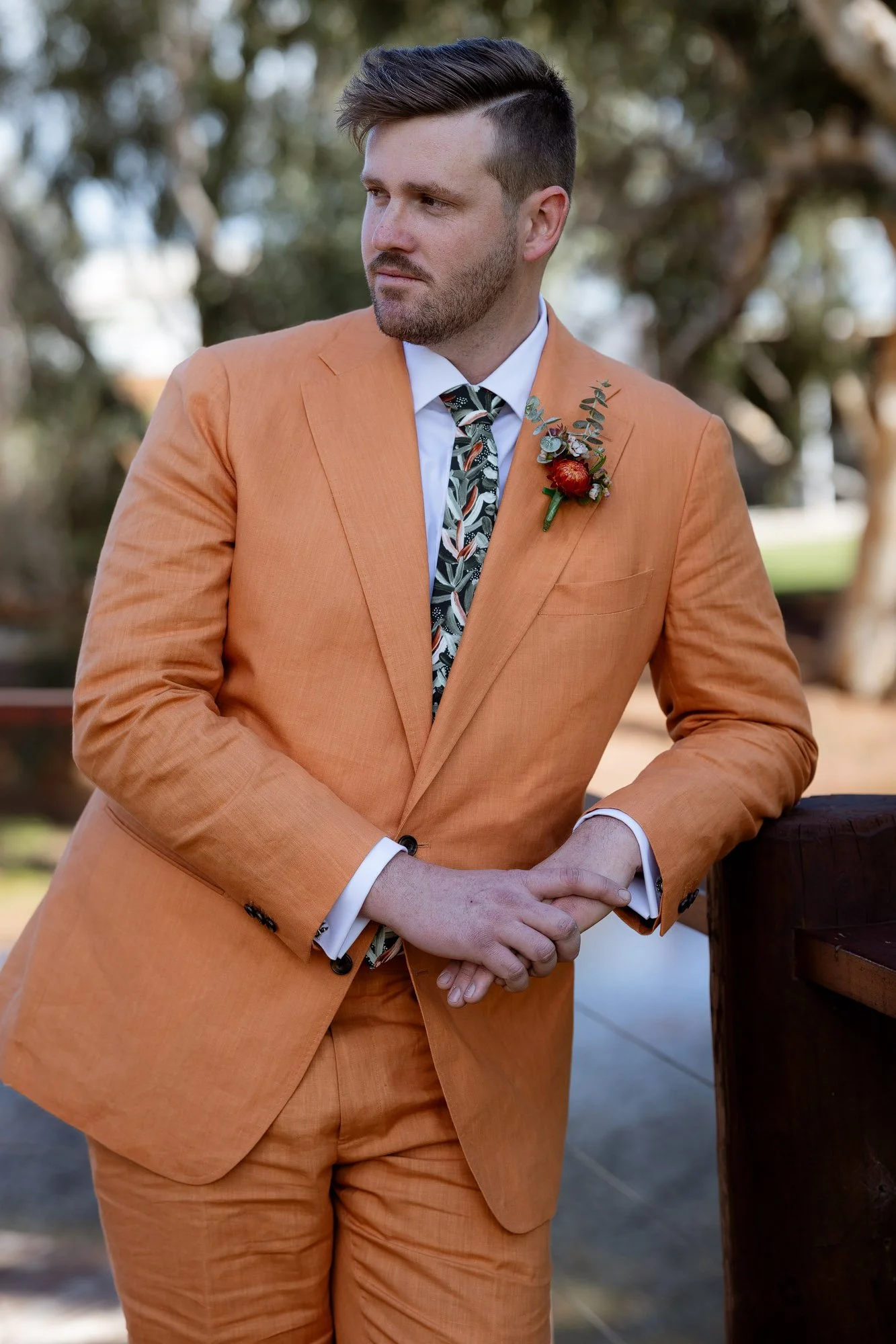 Groom standing on bridge looking over shoulder