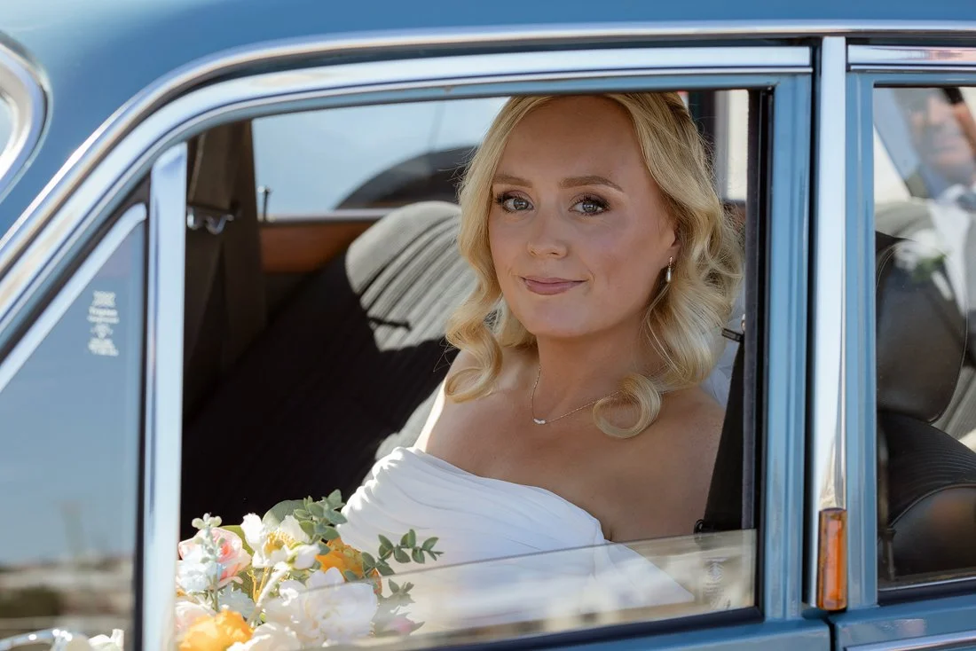 Bride sitting in bridal car looking out window