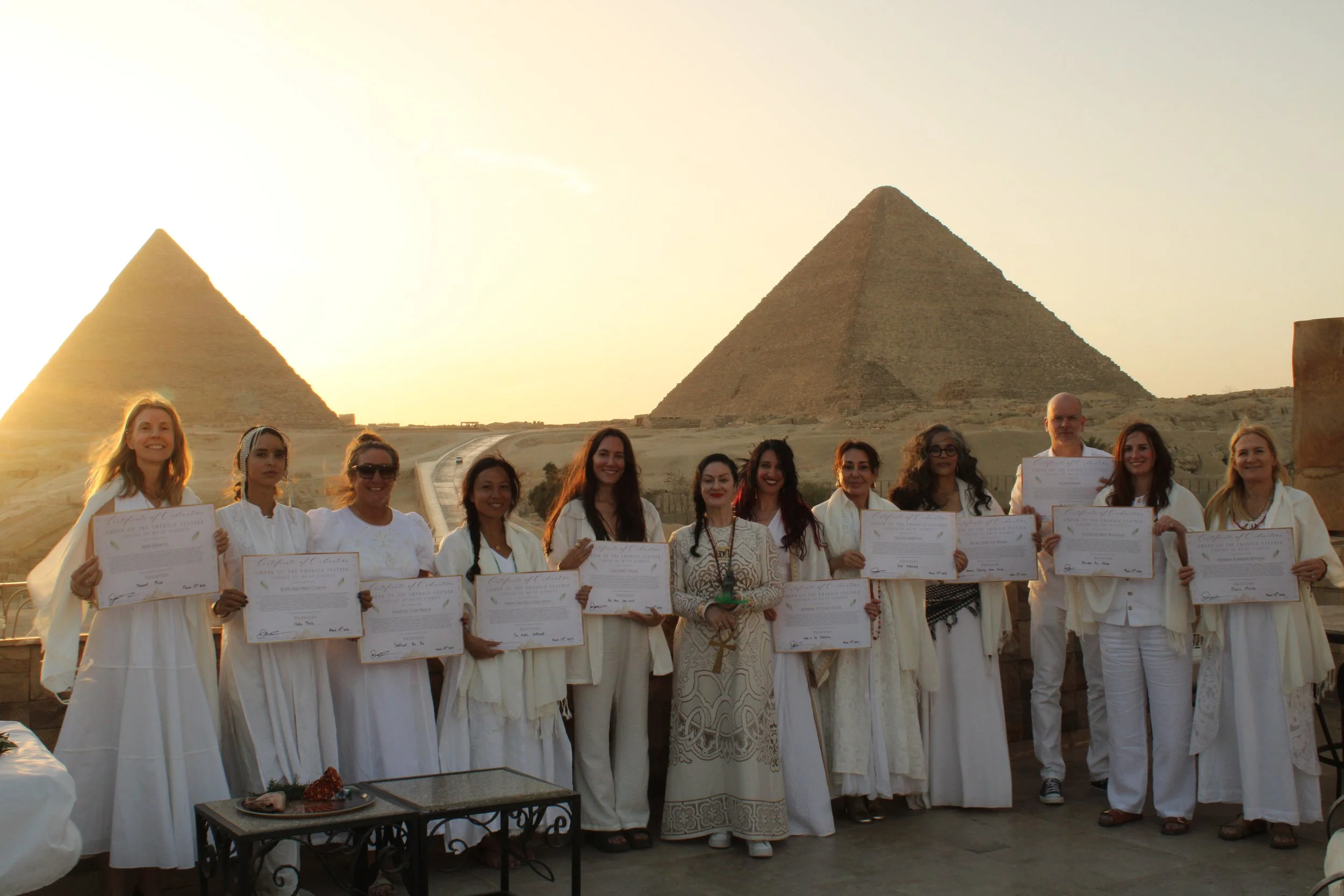 initiates dressed in white in front of the egyptian pyramids for ordination ceremony