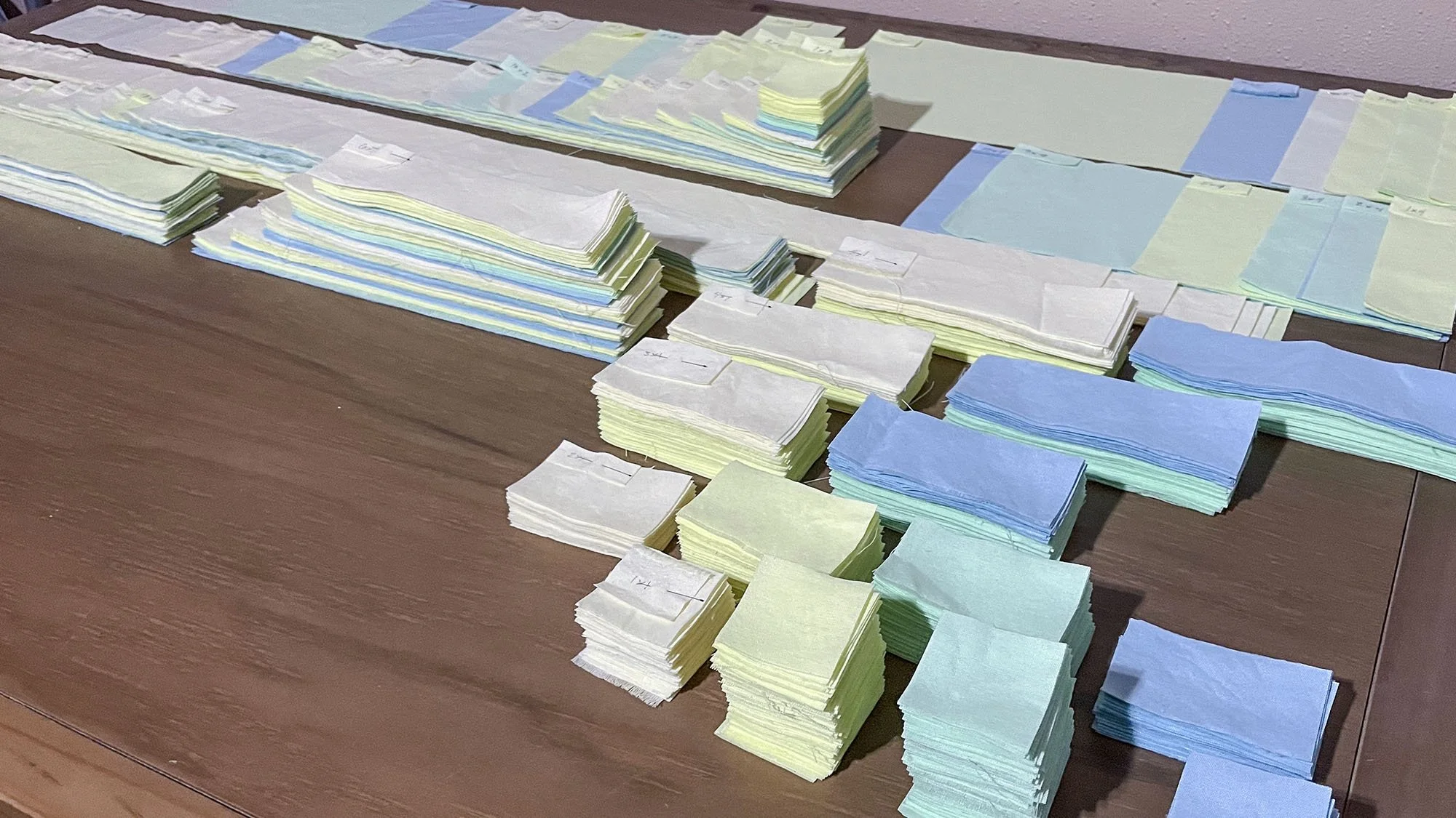 Cut fabric rectangles sorted into labeled stacks before assembling the quilt top.