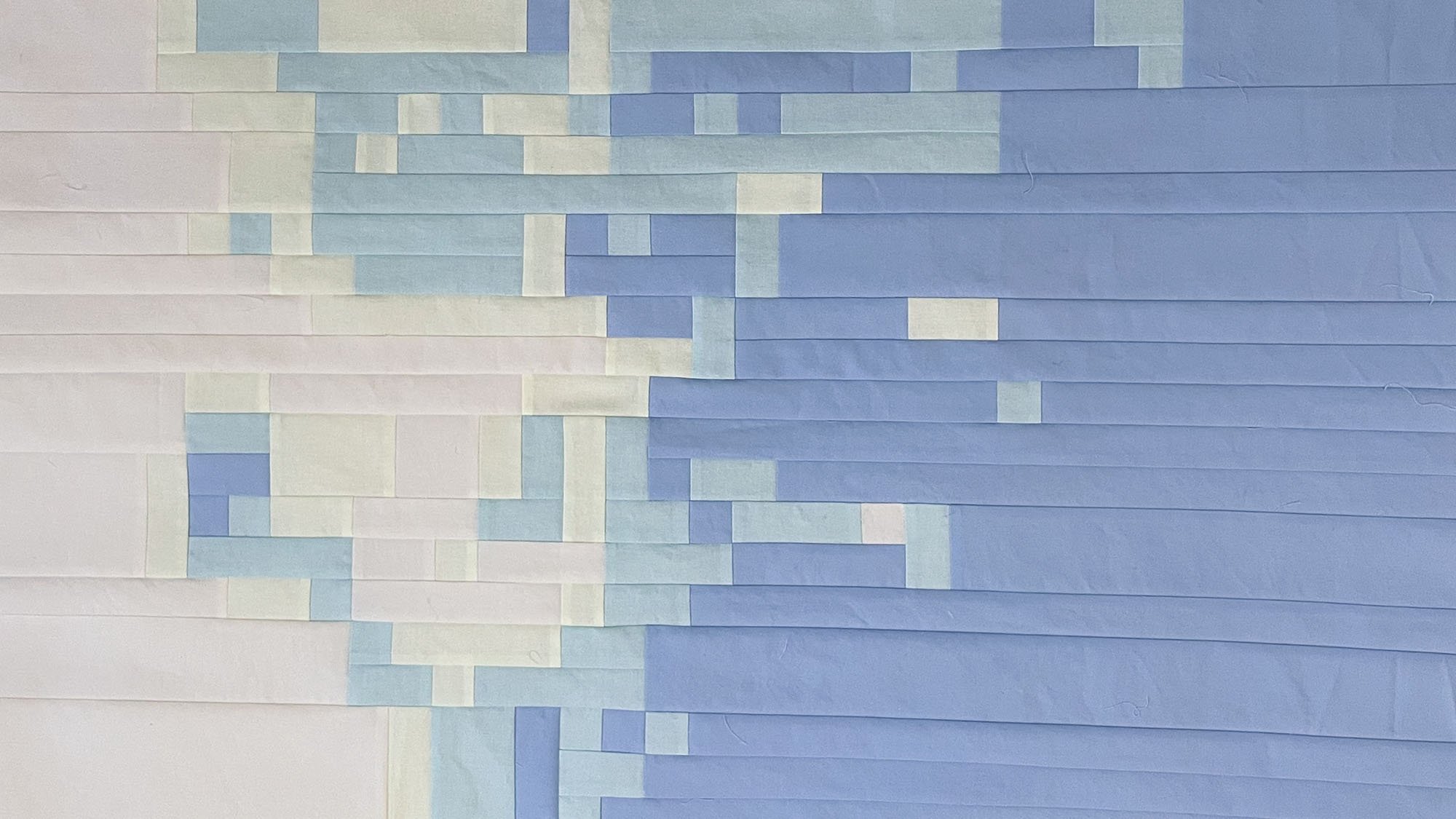 Early section of the pieced quilt top showing horizontal bands of rectangular fabric shapes.