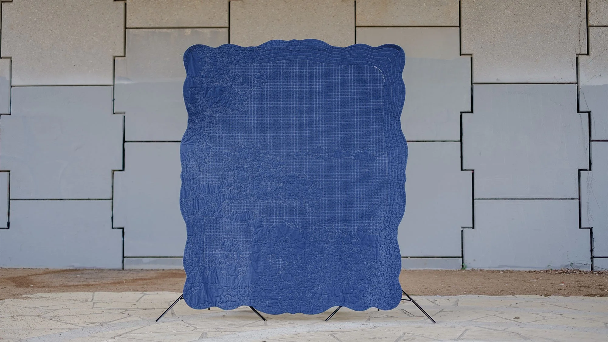 Back of the quilt showing dense quilting on blue backing fabric.