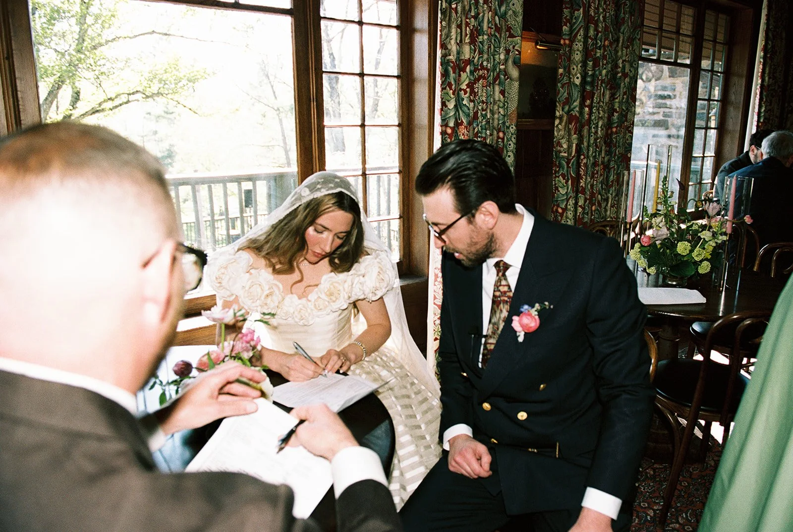 Candid film photo of the bride signing wedding documents beside the groom inside Deer Mountain Inn.