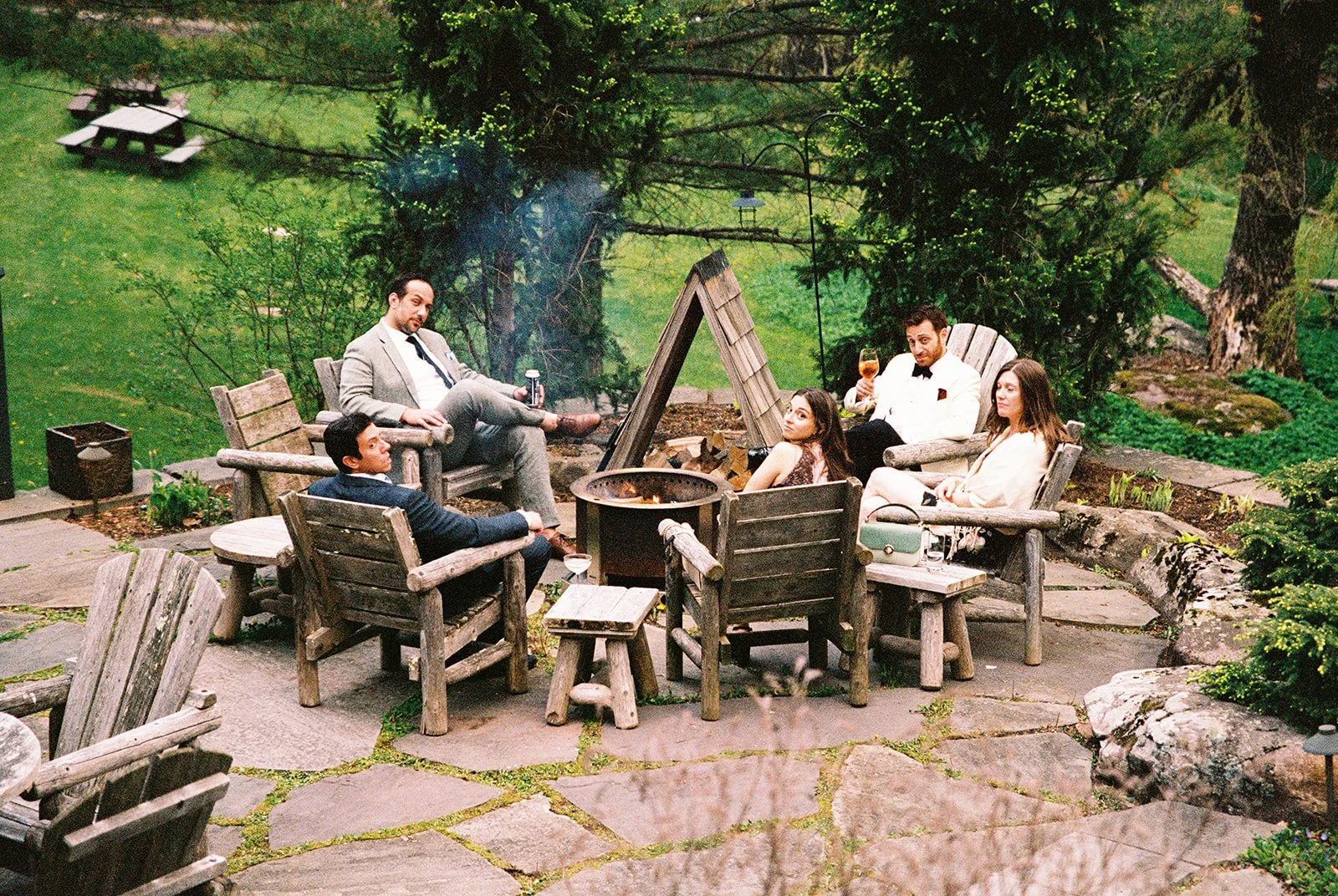 Film photo of wedding guests relaxing around a fire pit in the gardens at Deer Mountain Inn.