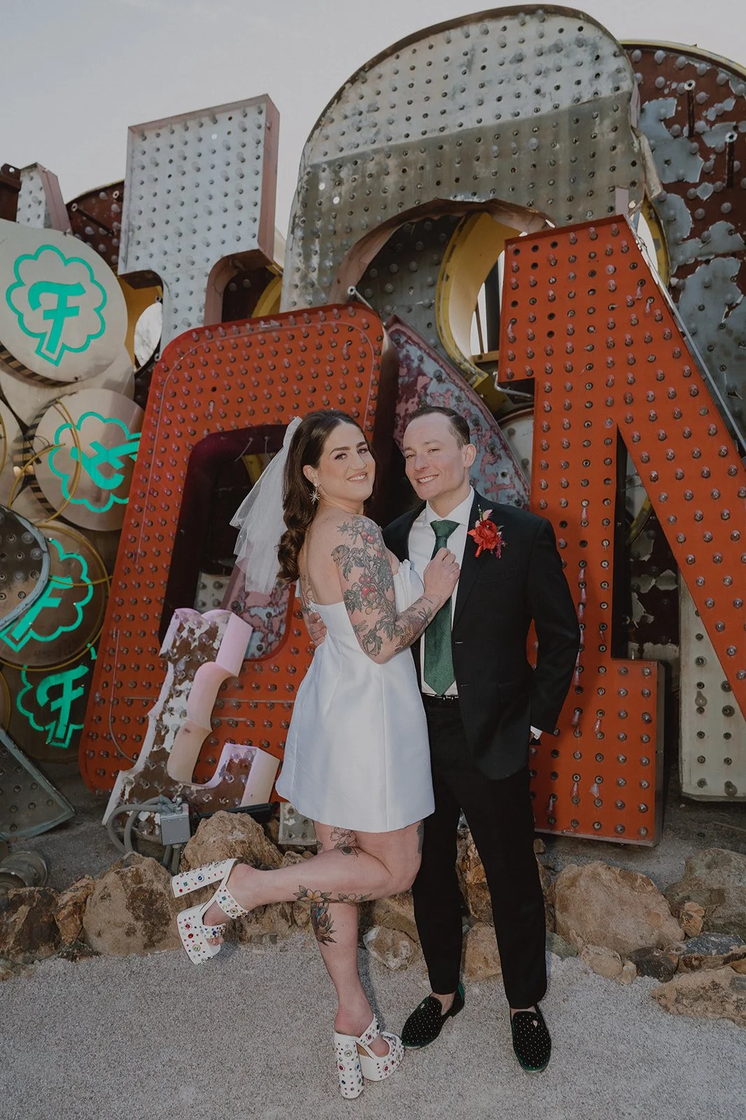 Bride and groom posing in front of colorful vintage signs in the North Gallery at the Neon Museum in Las Vegas.