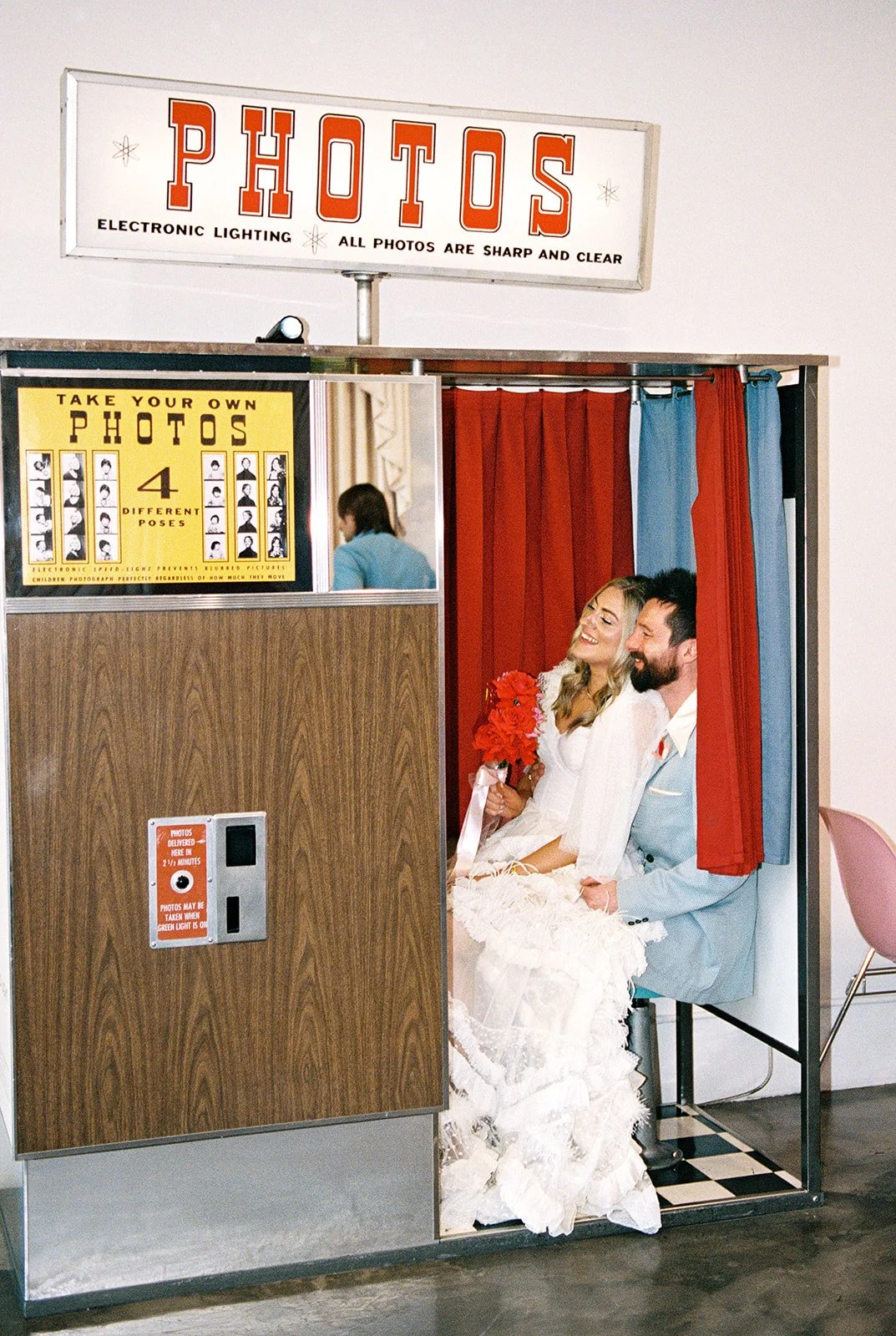 Couple taking photos inside the vintage analog photo booth at Sure Thing Chapel in Las Vegas on 35mm film.