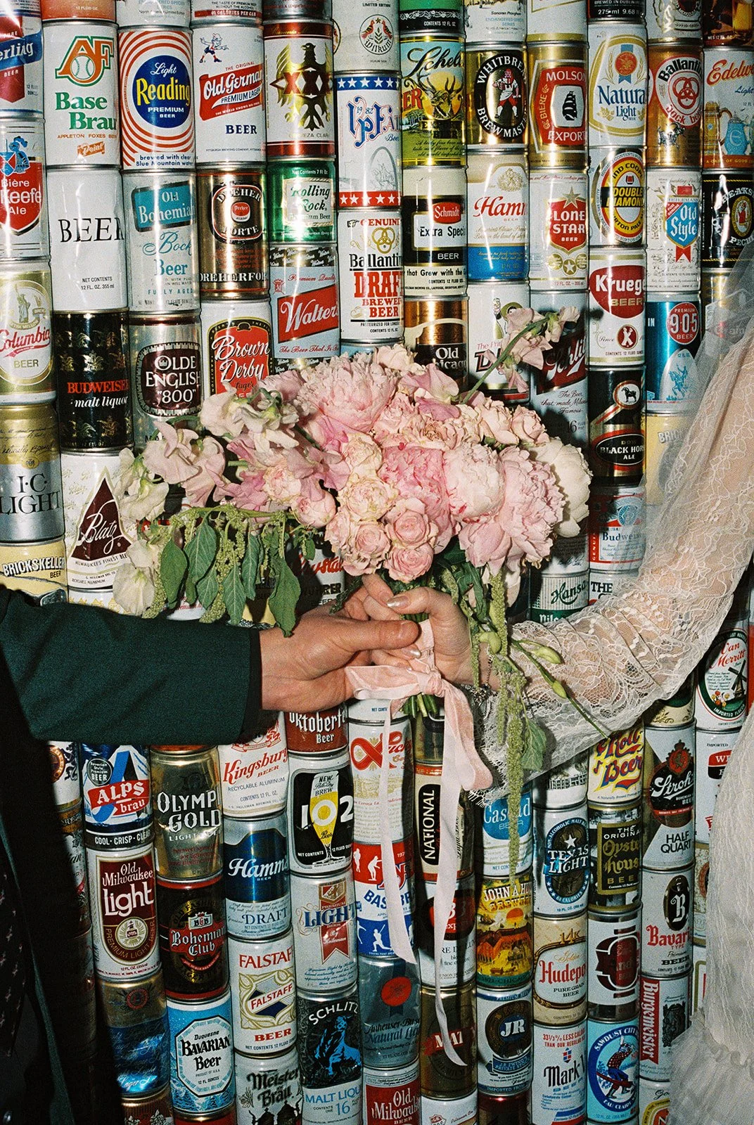 Couple holding a bouquet in front of a vintage beer can wall at The Silver Stamp in Las Vegas.