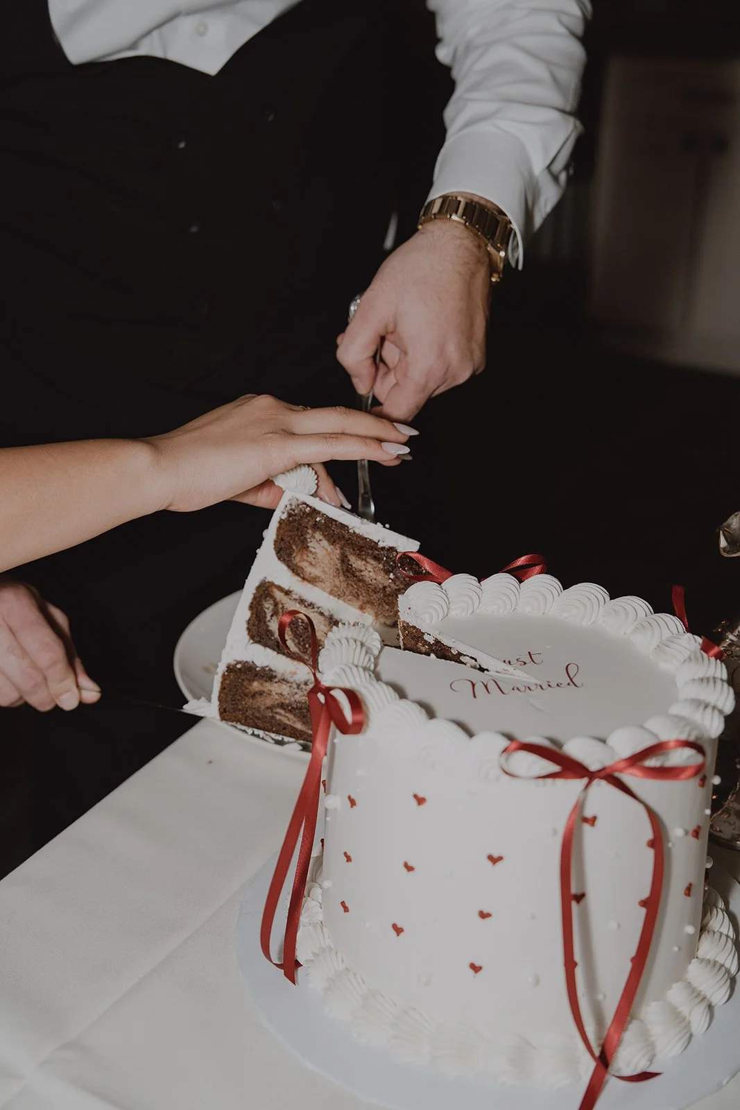 Close up photo of a bride and groom cutting into their wedding cake.