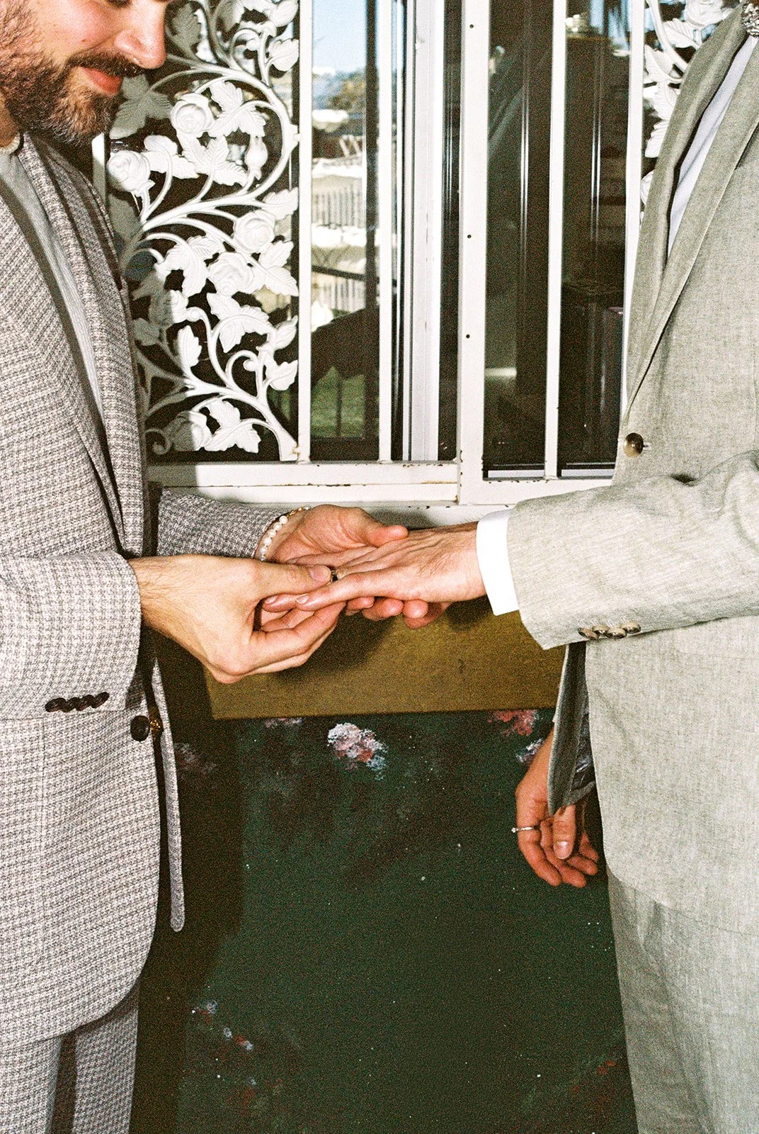 Groom putting the ring on the grooms finger during their ceremony.