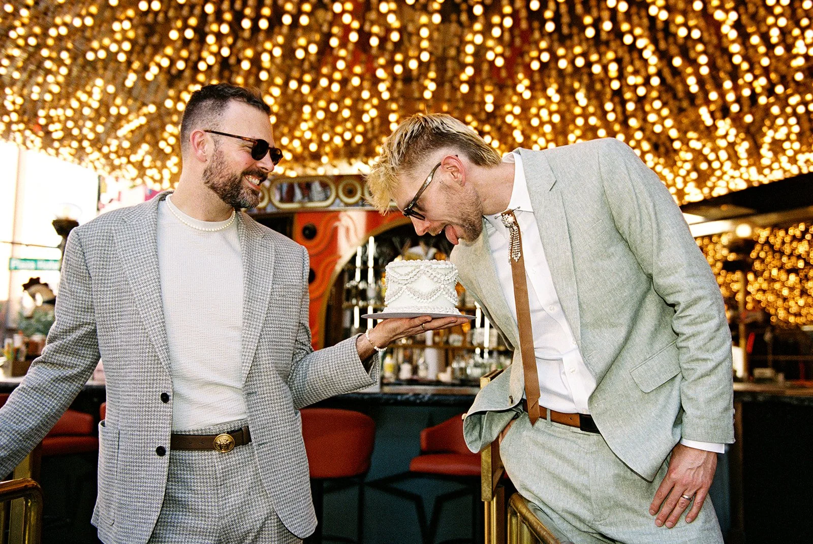 Couple taking playful photos with their vintage-0inspired Las Vegas elopement cake by Winston Marie Cakes.