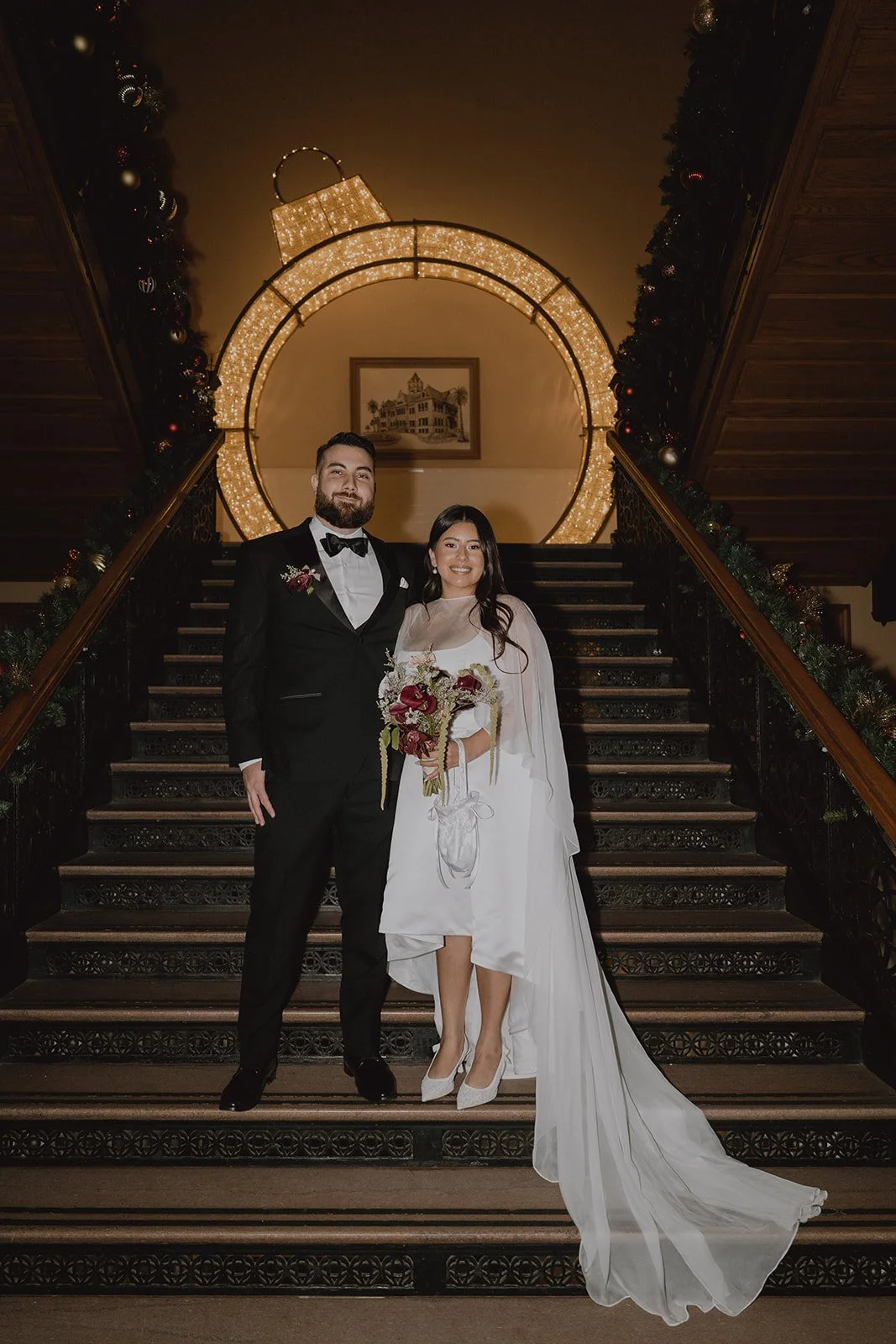 Bride and groom posing on the staircase for their Old Orange County Courthouse wedding portraits.