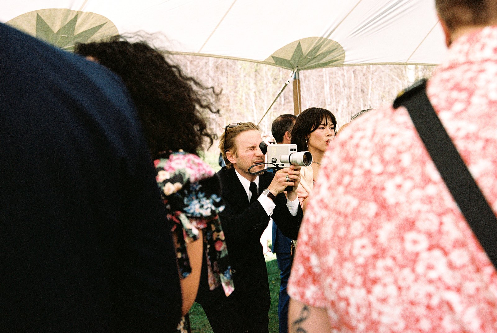 Guest taking video of an outdoor wedding ceremony.