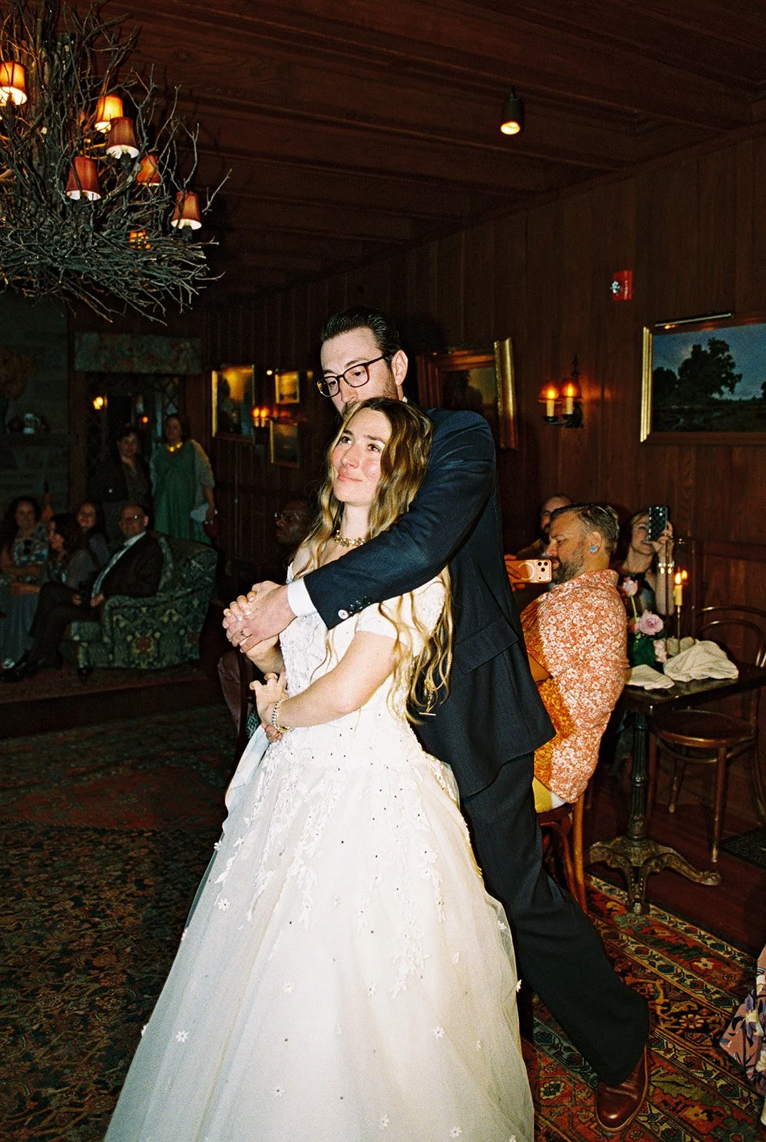 Candid film photo of the groom embracing the bride from behind during their wedding reception at Deer Mountain Inn.