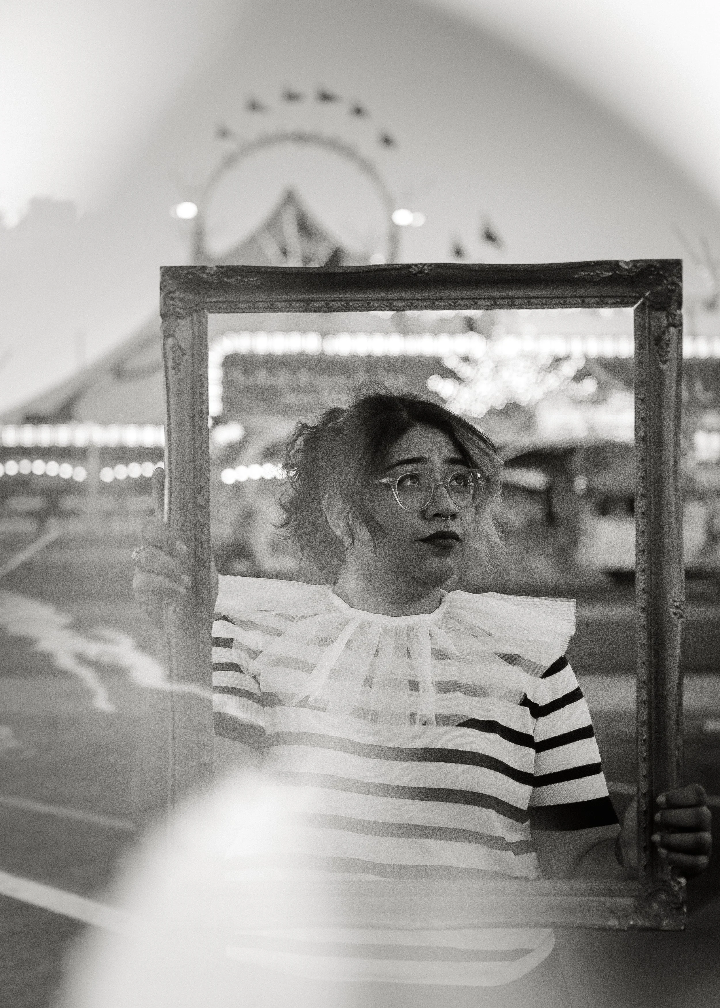 Black and white photo of Cruz, owner of Cruz Valentin Photography, posing inside a frame at the fair.