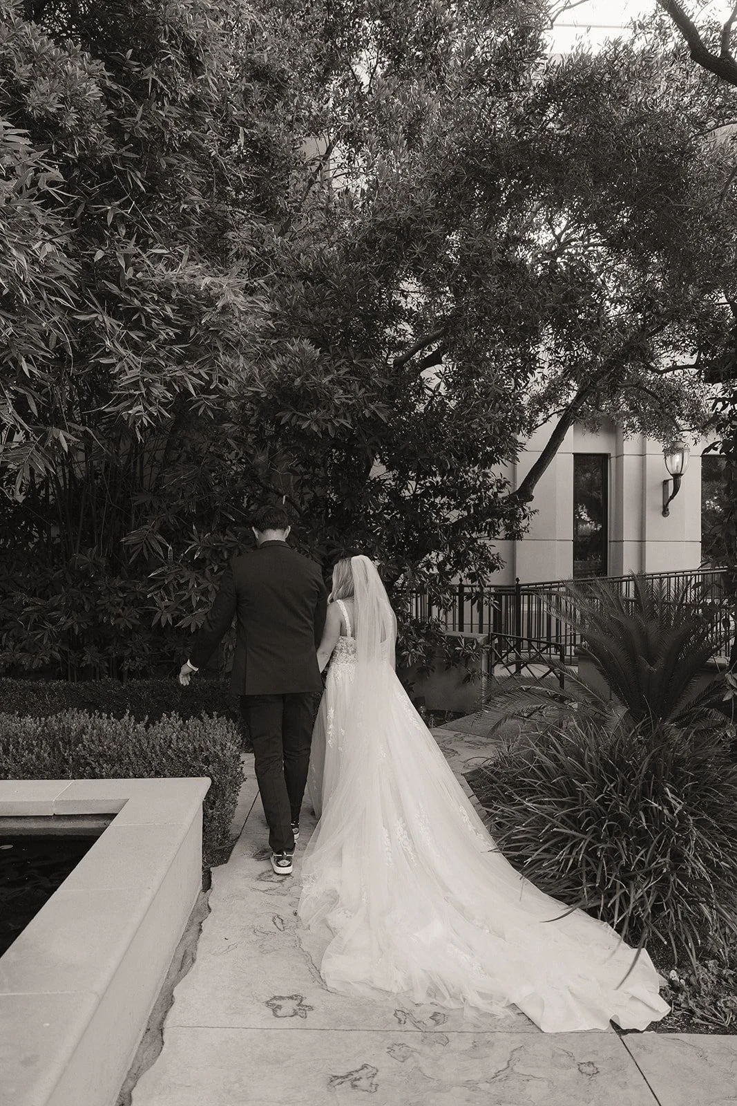 Black and white photo of a bride and groom walking off together after their Caesars Palace Venus Garden wedding ceremony