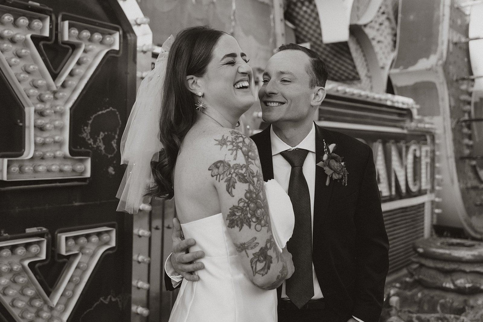 Close-up black and white portrait of the bride laughing as the groom leans in during Neon Museum couple portraits.