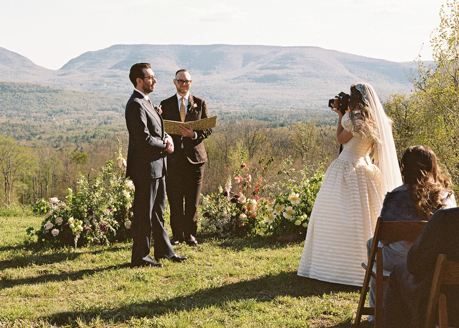 Bride taking a film portrait of the groom during their ceremony.