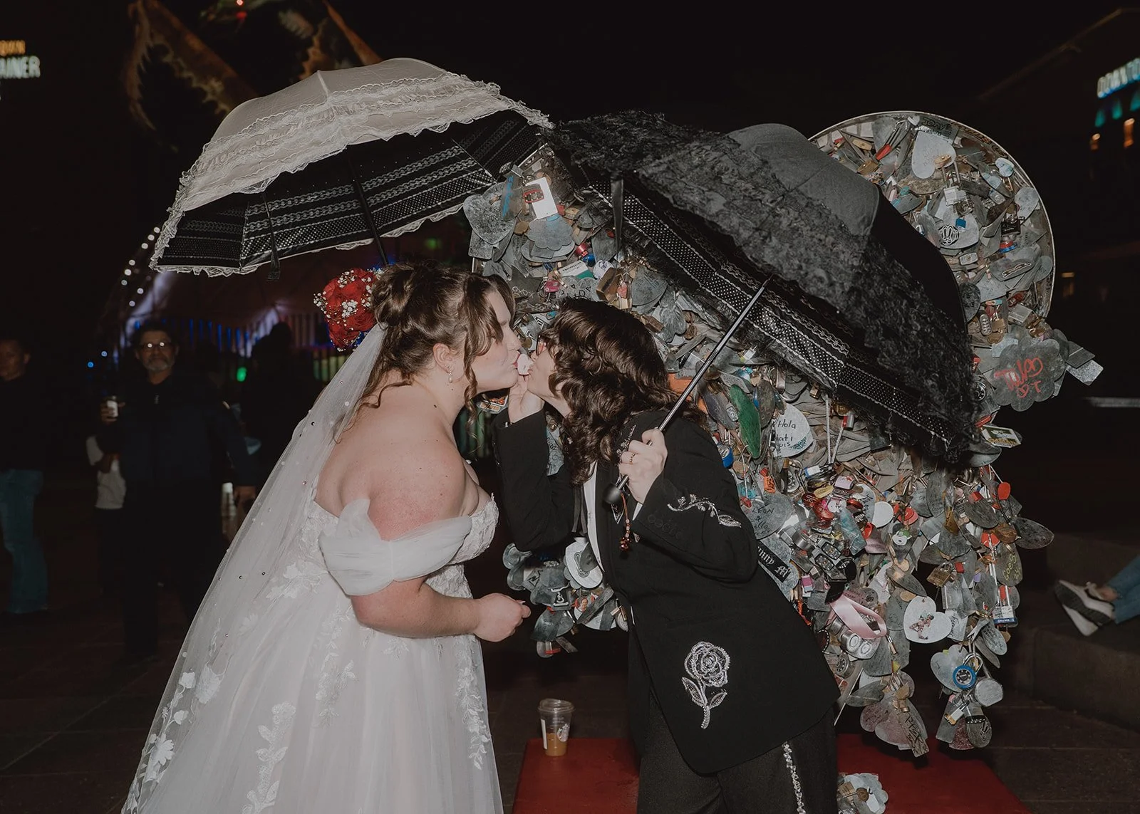 Couple kissing under umbrellas beside the Love Locket sculpture in Downtown Las Vegas.