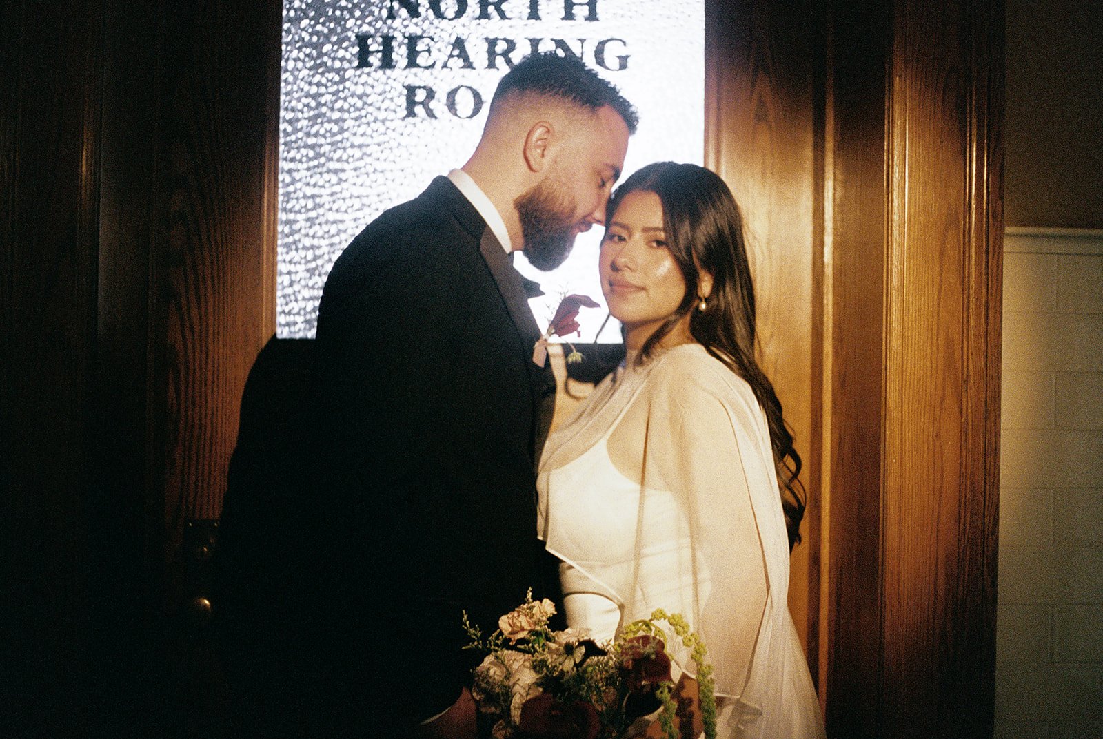 35mm film photo of a couple posing outside of the North Hearing Room at Old Orange County Courthouse.