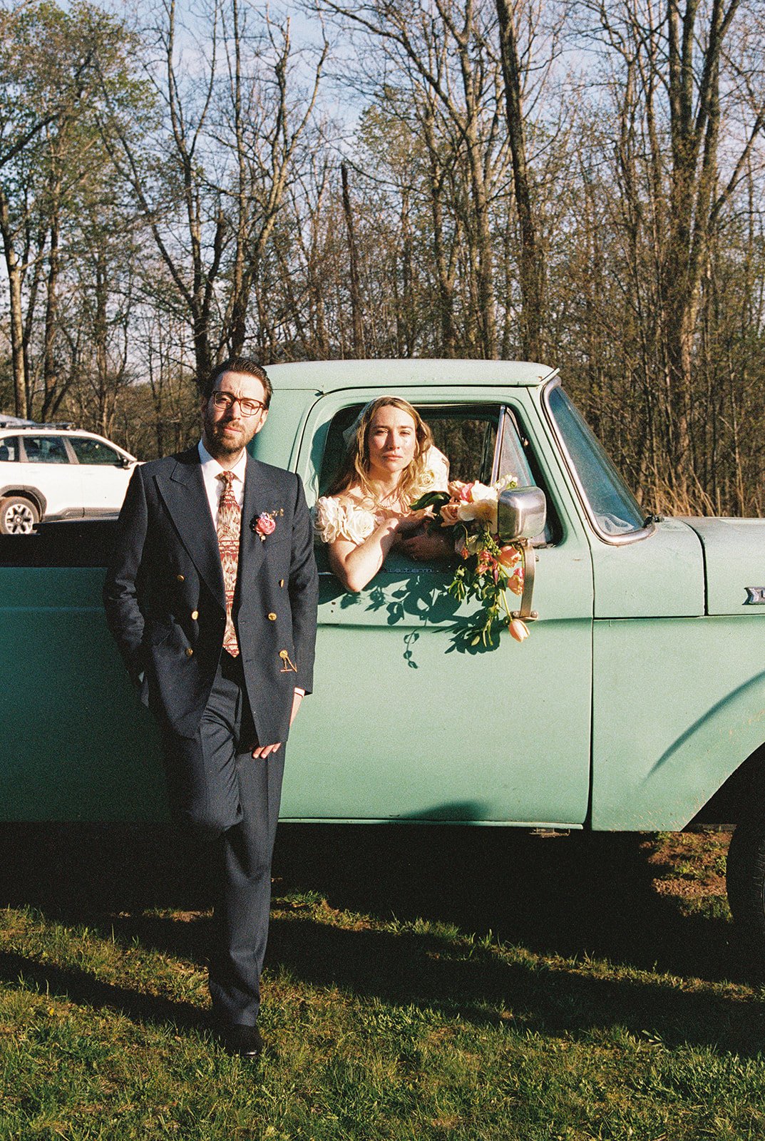 Bride and groom posing for portraits with a vintage green truck.